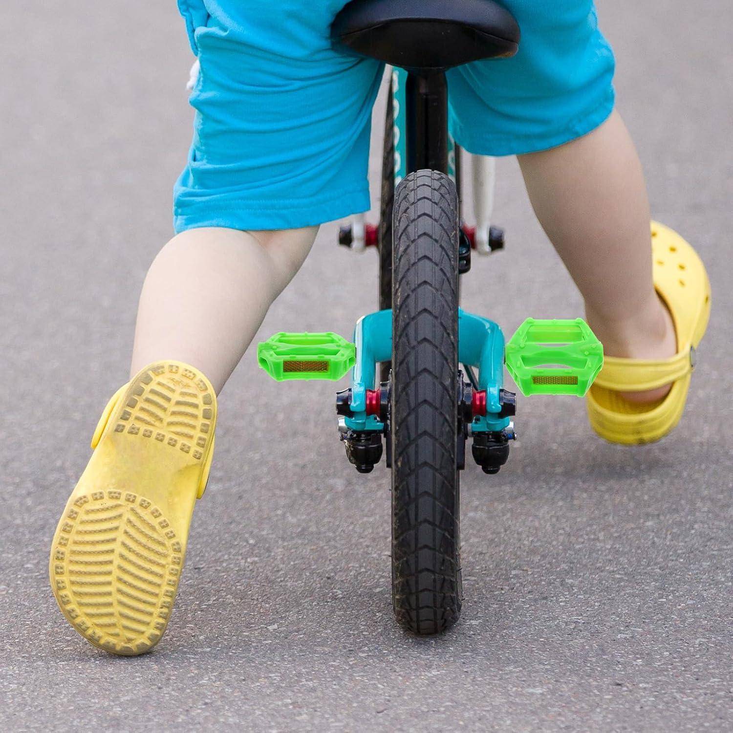 Nahaufnahme eines Kindes, das auf einem Fahrrad fährt, mit gelben Schuhen, die auf einer gepflasterten Straße in die Pedale treten.