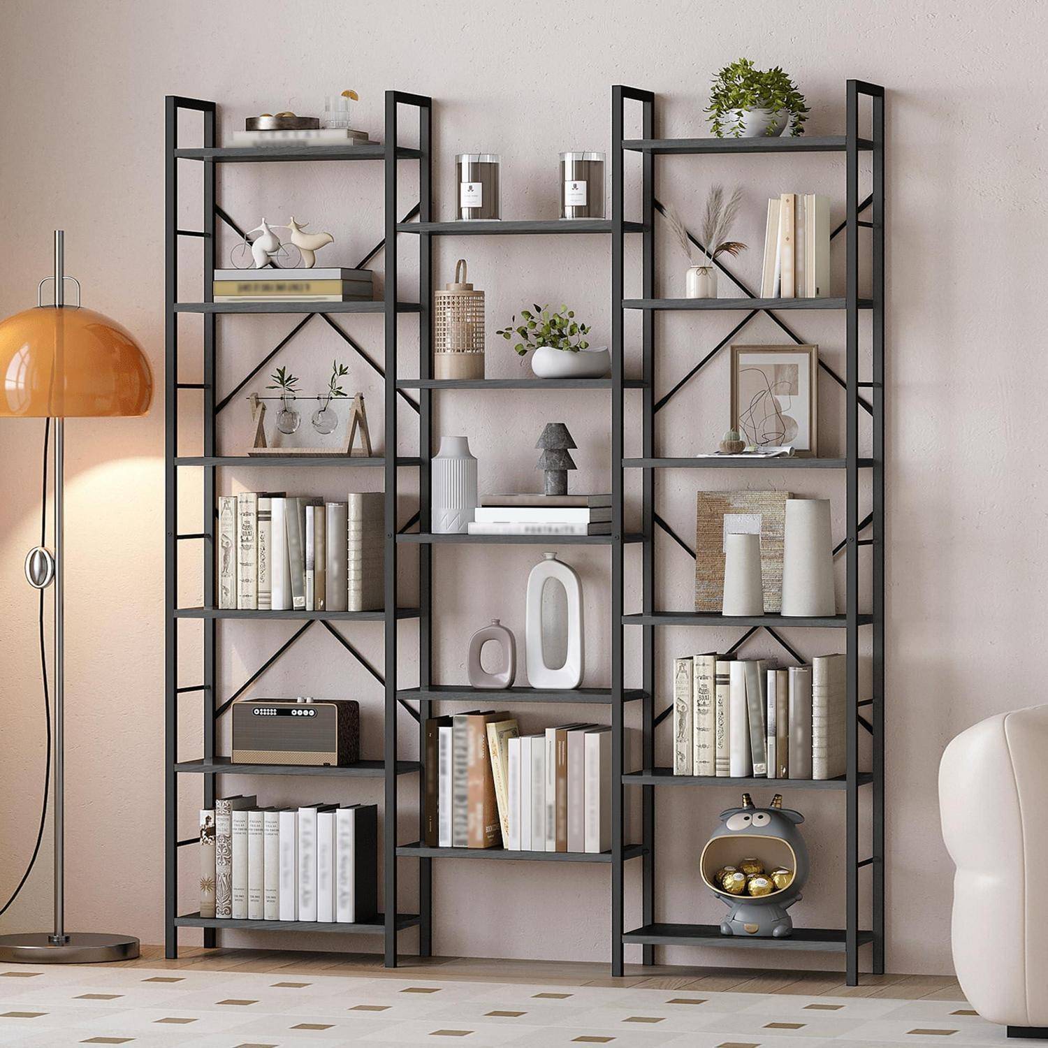 Drei schwarze Metallregale an einer beigen Wand stellen Bücher, Vasen, Pflanzen, gerahmte Kunstwerke und Dekoration neben einer orangefarbenen Stehlampe aus.