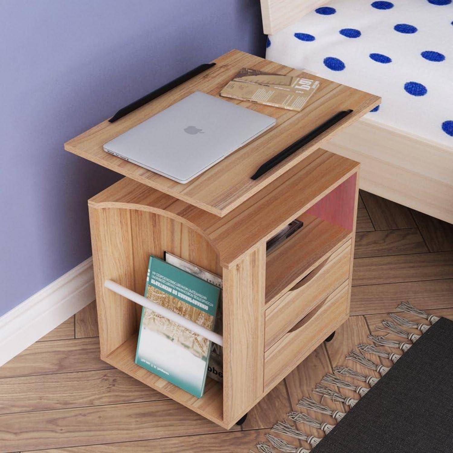 Holzerner Nachttisch/Wagen neben einem Bett, mit einem Laptop oben drauf, Buchablage an der Seite und einem kleinen Regal für persönliche Gegenstände.