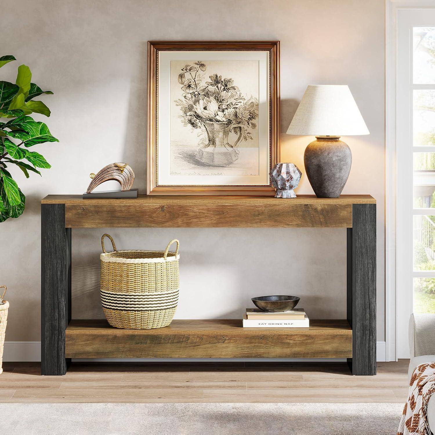 Holzkonsole mit gerahmten botanischen Kunstwerken, Tischleuchte, Körben und Dekoration in einem hellen Wohnzimmer.