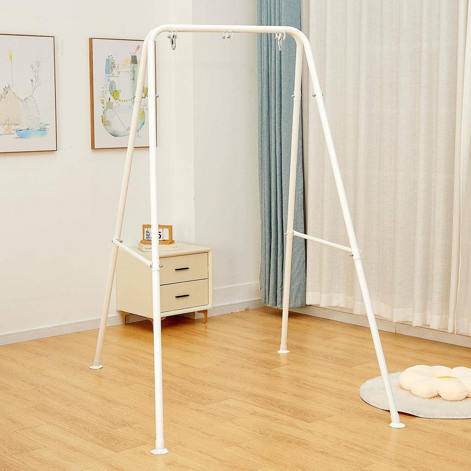 Weißes freistehendeses Kleidergestell im leeren Zimmer mit Holzboden, neben einem kleinen Nachttisch und Vorhängen.