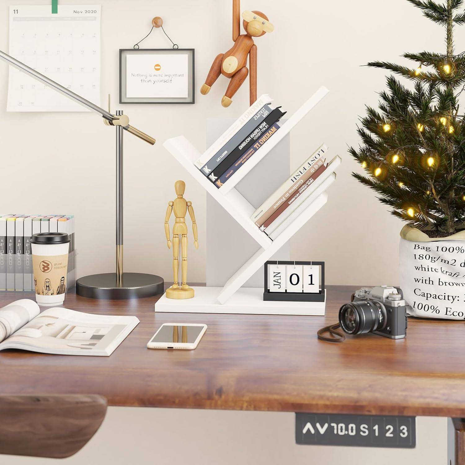 Stilvolle Schreibtischszene mit Lampe, Büchern auf weißem X-förmigem Regal, Kalender mit Anzeige des 01. Januar, Kamera, Telefon und leuchtender Weihnachtsdekoration.