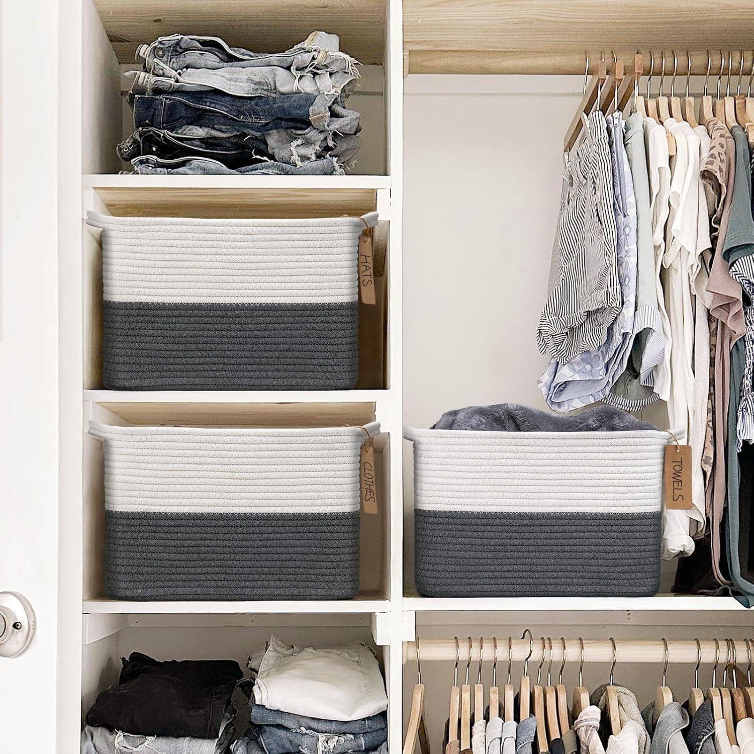 Offener Kleiderschrank mit ordentlich organisierten Kleidern, gefalteten Jeans und beschrifteten Aufbewahrungskörben auf Regalen und Kleiderstangen.