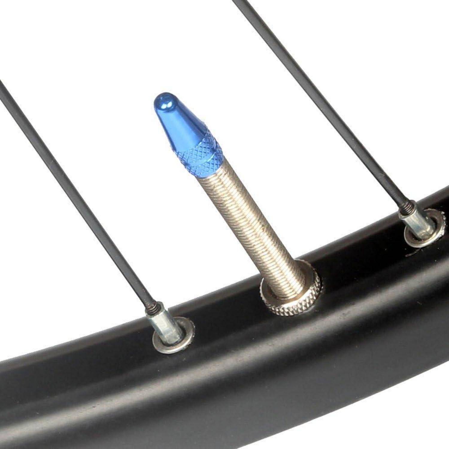 Nahaufnahme eines Fahrradventils mit einer blauen Kappe neben Speichen auf einer schwarzen Felge.