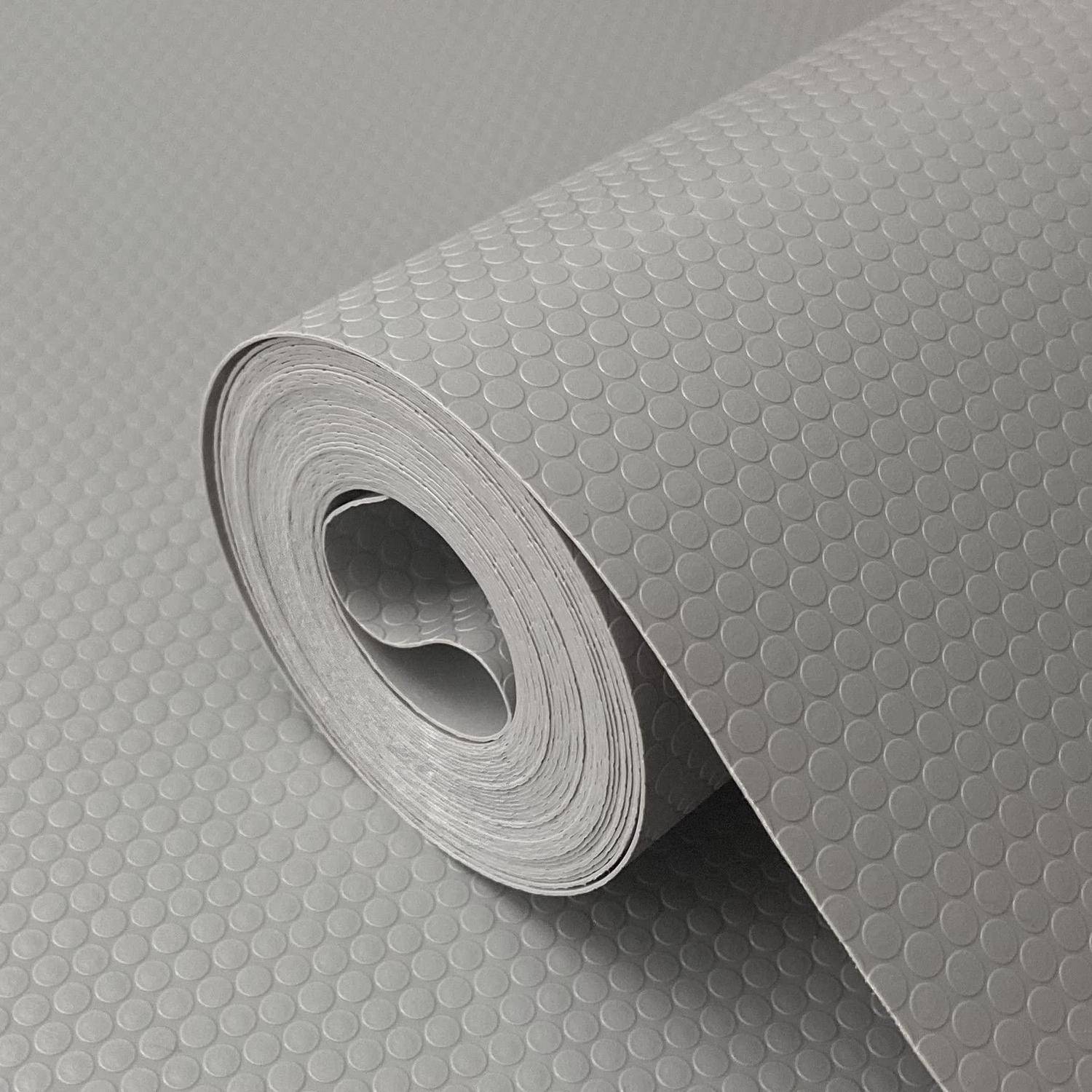 Aufgerollte grau strukturierte Vinyl- oder Bodenbelagsbahn mit erhabenenem Kreismuster, teilweise auf einer passenden Oberfläche ausgerollt dargestellt.