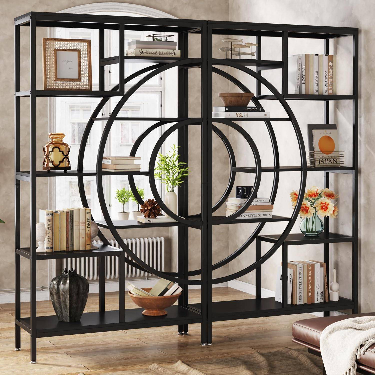 Schwarzes Metall-Bücherregal mit geometrischem Design und kreisförmiger Mittelmotiv, das Bücher, Vasen, gerahmte Kunstwerke und Blumen in einem hellen Raum präsentiert