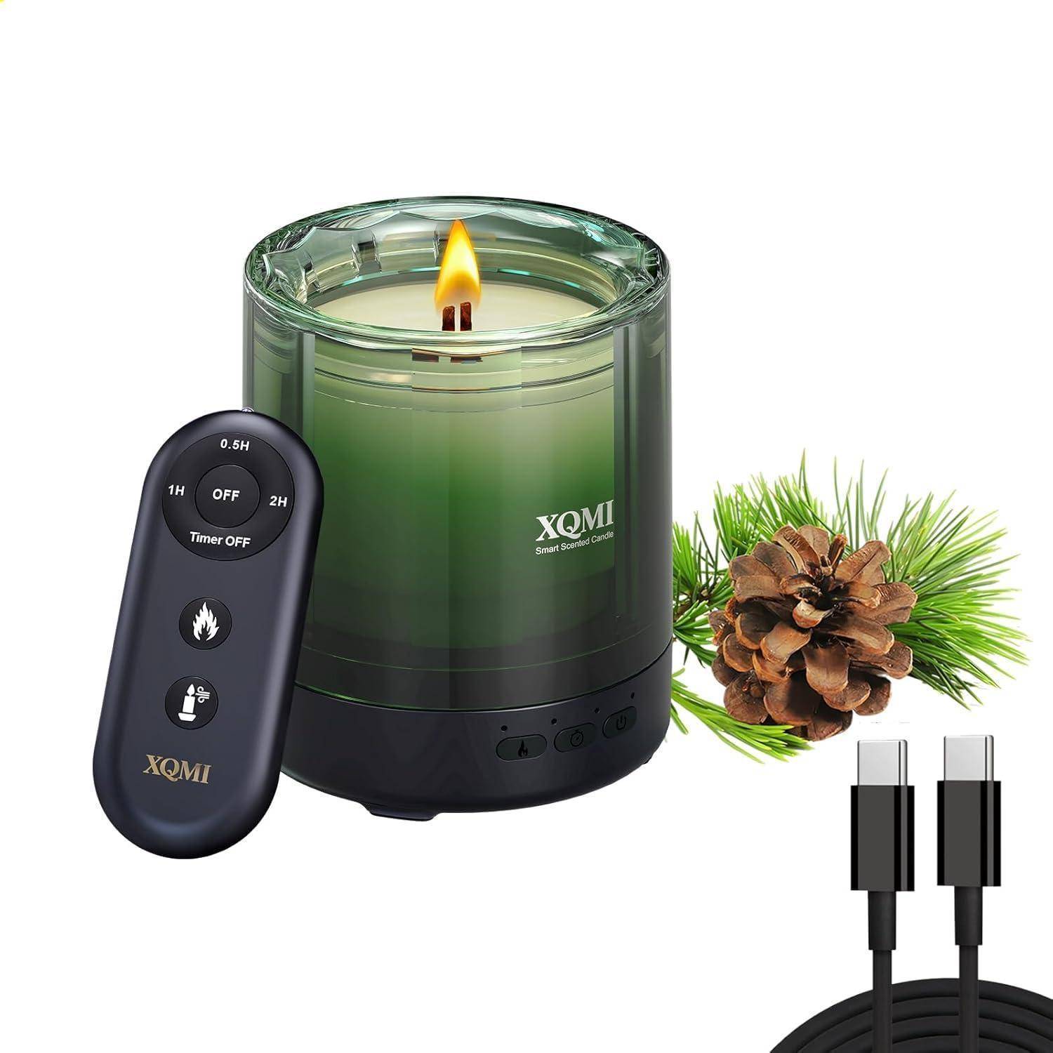 Grüne XQMI-Kerze ohne Flamme mit Fernbedienung und Timer, Tannenzapfen-Dekoration und USB-Ladekabel auf weißem Hintergrund.
