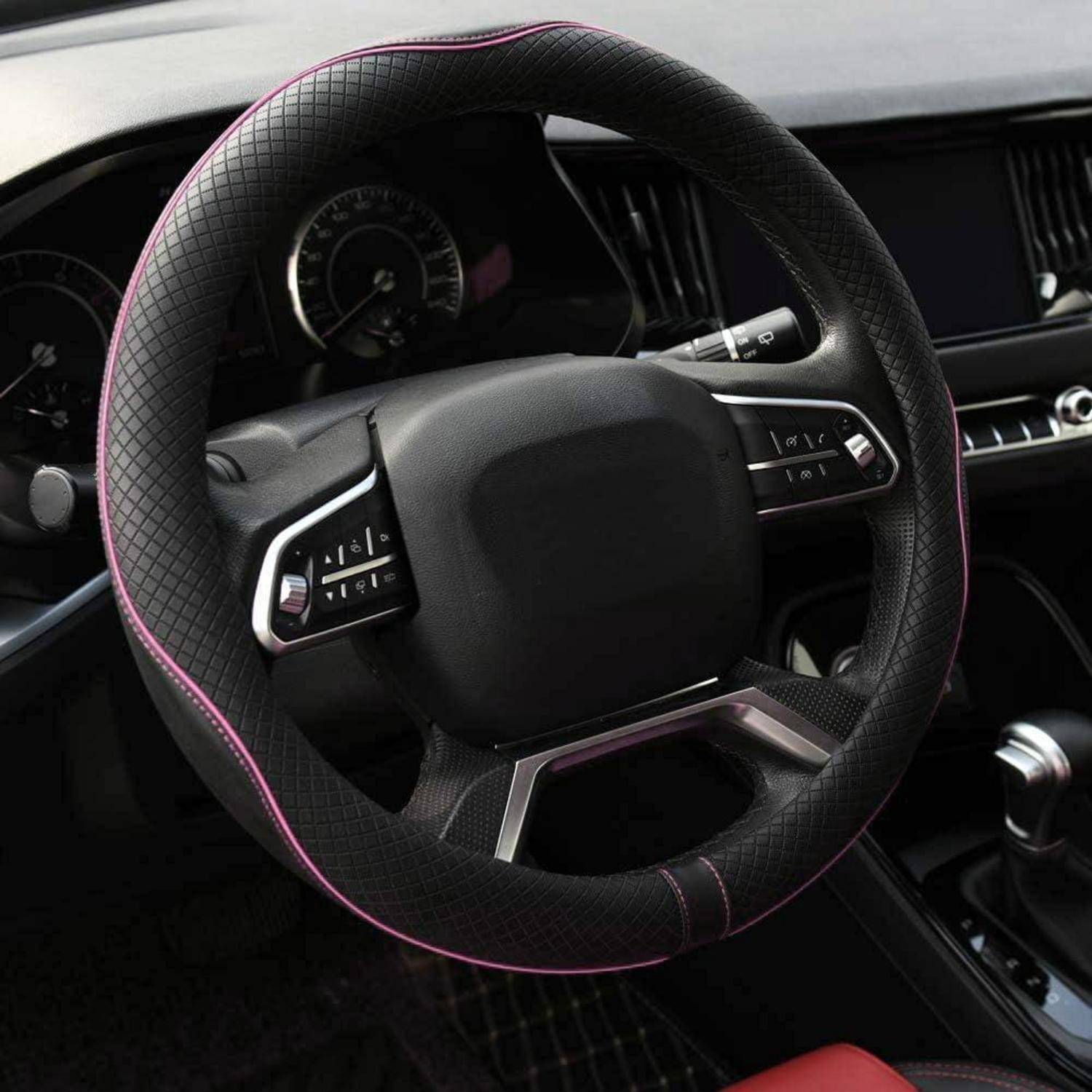 Nahaufnahme eines Autolenkrads mit schwarzem strukturiertem Bezug, rosa Nähten und integrierten Bedienungstasten in einem modernen Armaturenbrett.