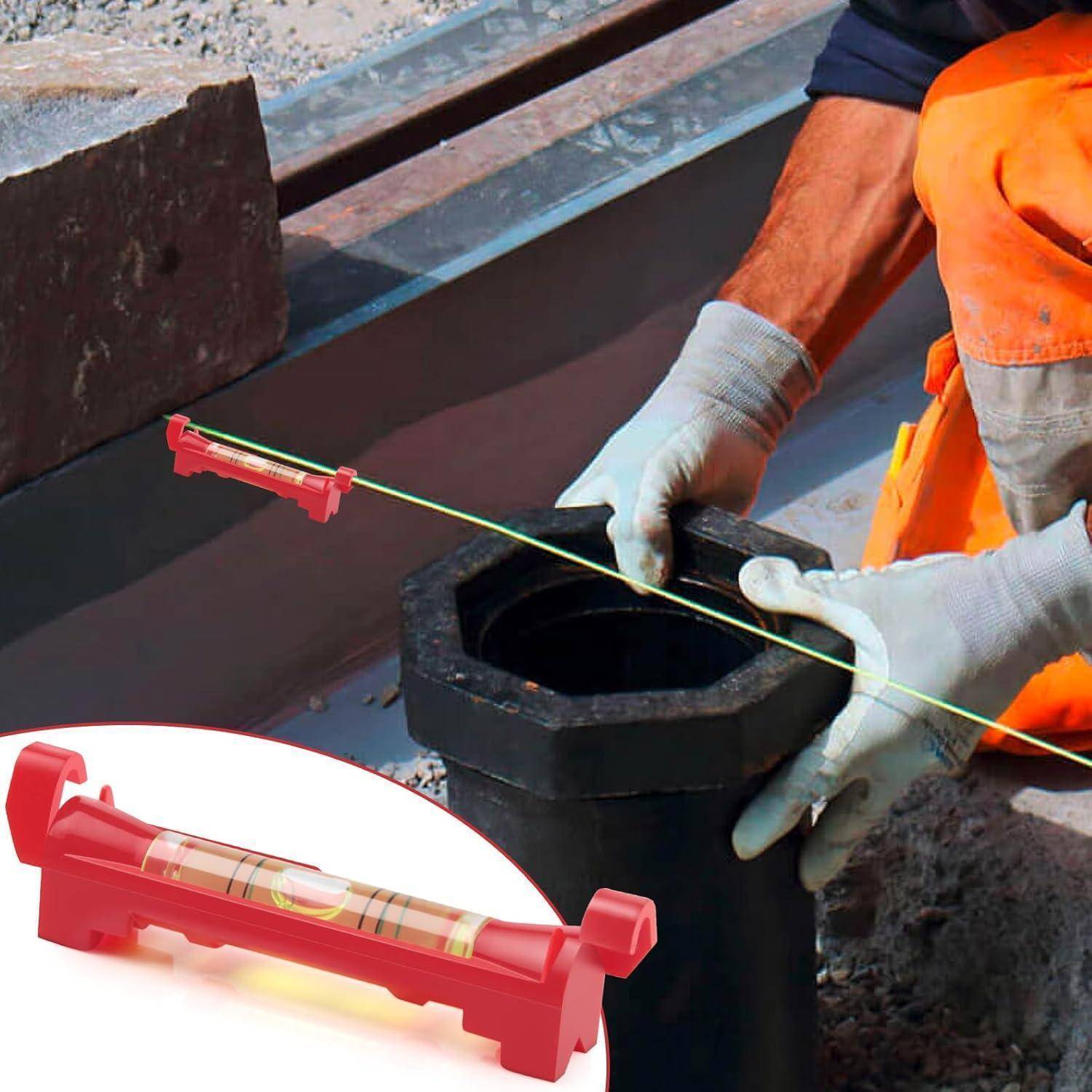 Bauarbeiter verwendet eine Schnurlibelle, um eine schwarze sechseckige Rohrarmatur auf einer Baustelle auszurichten; die Vergrößerung zeigt das rote Libellenwerkzeug.