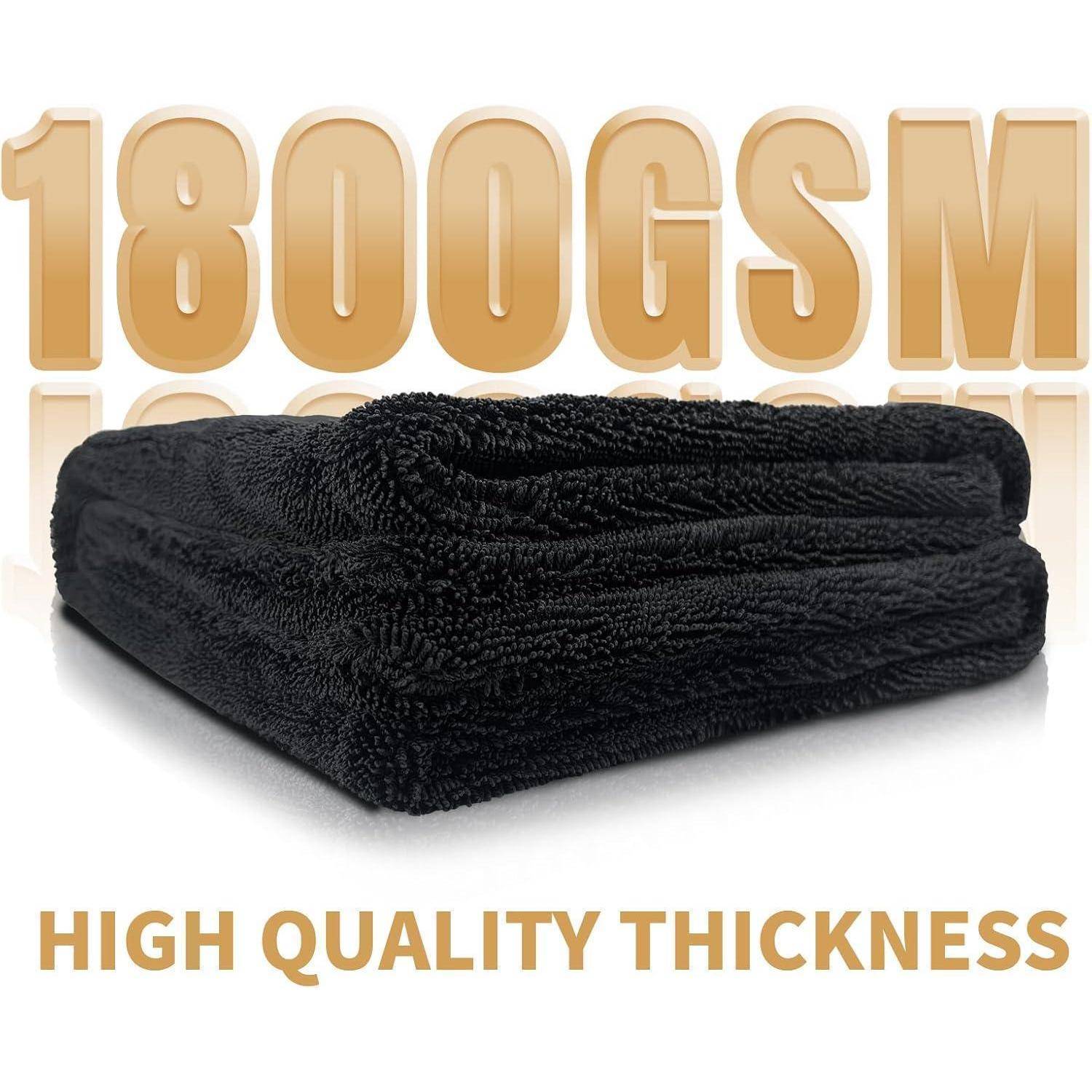 Gefaltetes schwarzes Mikrofaser-Handtuch mit goldenem Text '1800GSM' und 'HIGH QUALITY THICKNESS' auf weißem Hintergrund.