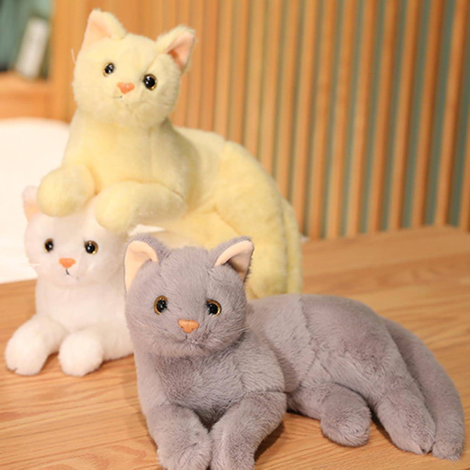 Drei kuschelige Katzenmspielzeuge in Grau, Creme und Blassgelbœ auf einer Holzoberfläche mit gestreiftem Hintergrund posiert.
