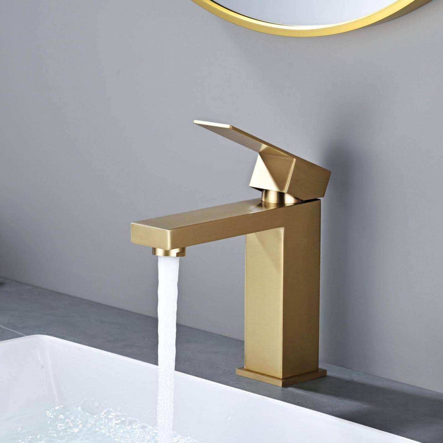 Moderner goldener Badezimmerhahn mit fließendem Wasser in ein weißes Waschbecken vor einer grauen Wand.