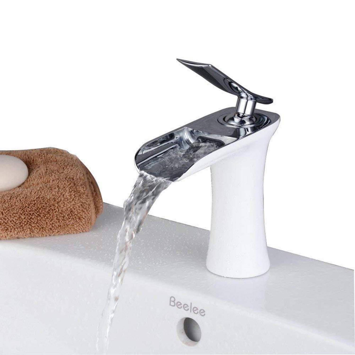 Kleiner verchromter Wasserfallhahn, der Wasser in ein weißes Waschbecken gießt, mit einem braun gefalteten Handtuch daneben.