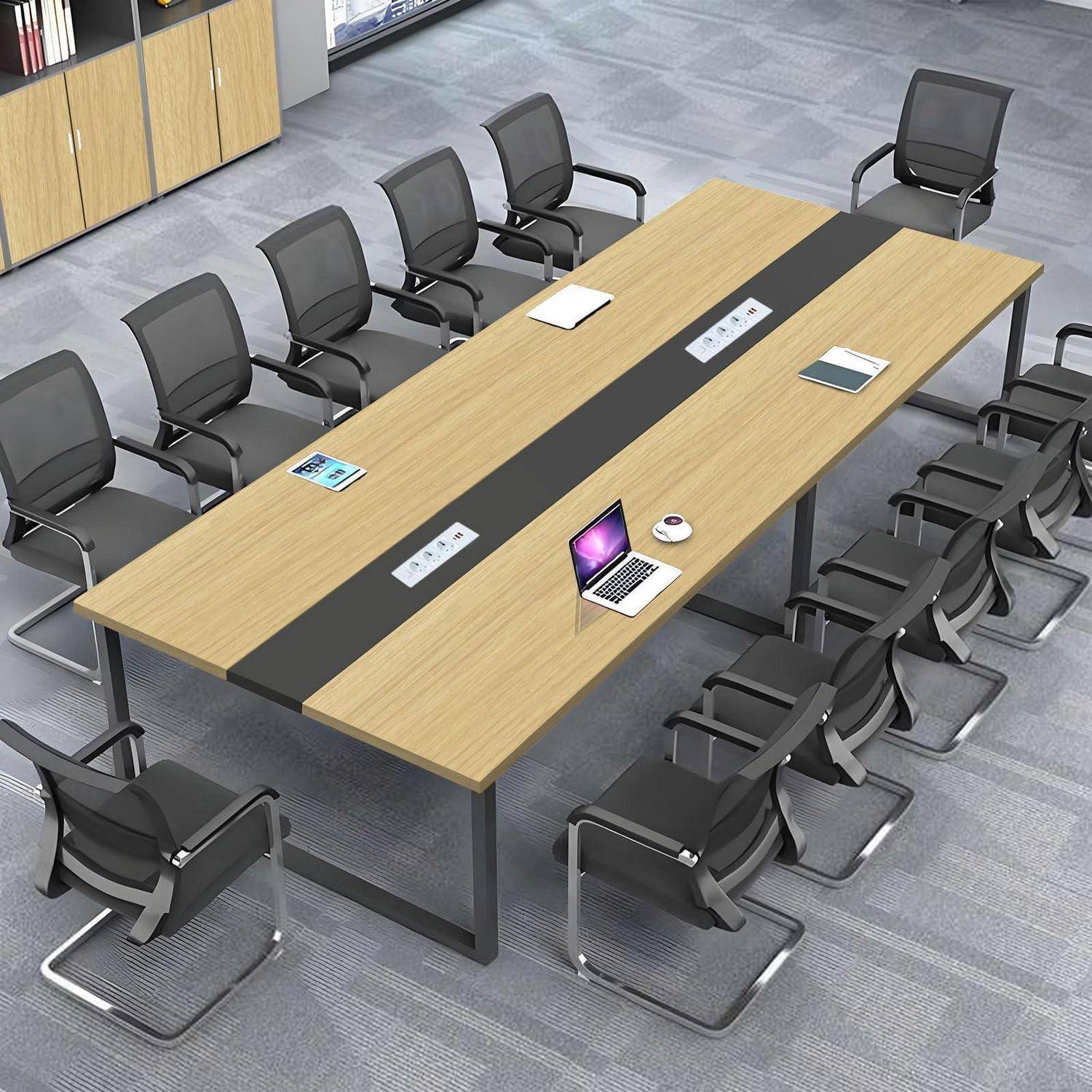 Moderner Konferenzraum mit einem großen rechteckigen Tisch, umgeben von leeren schwarzen Bürostühlen; auf dem Tisch liegen Laptops, Notizbücher und eine Tasse.