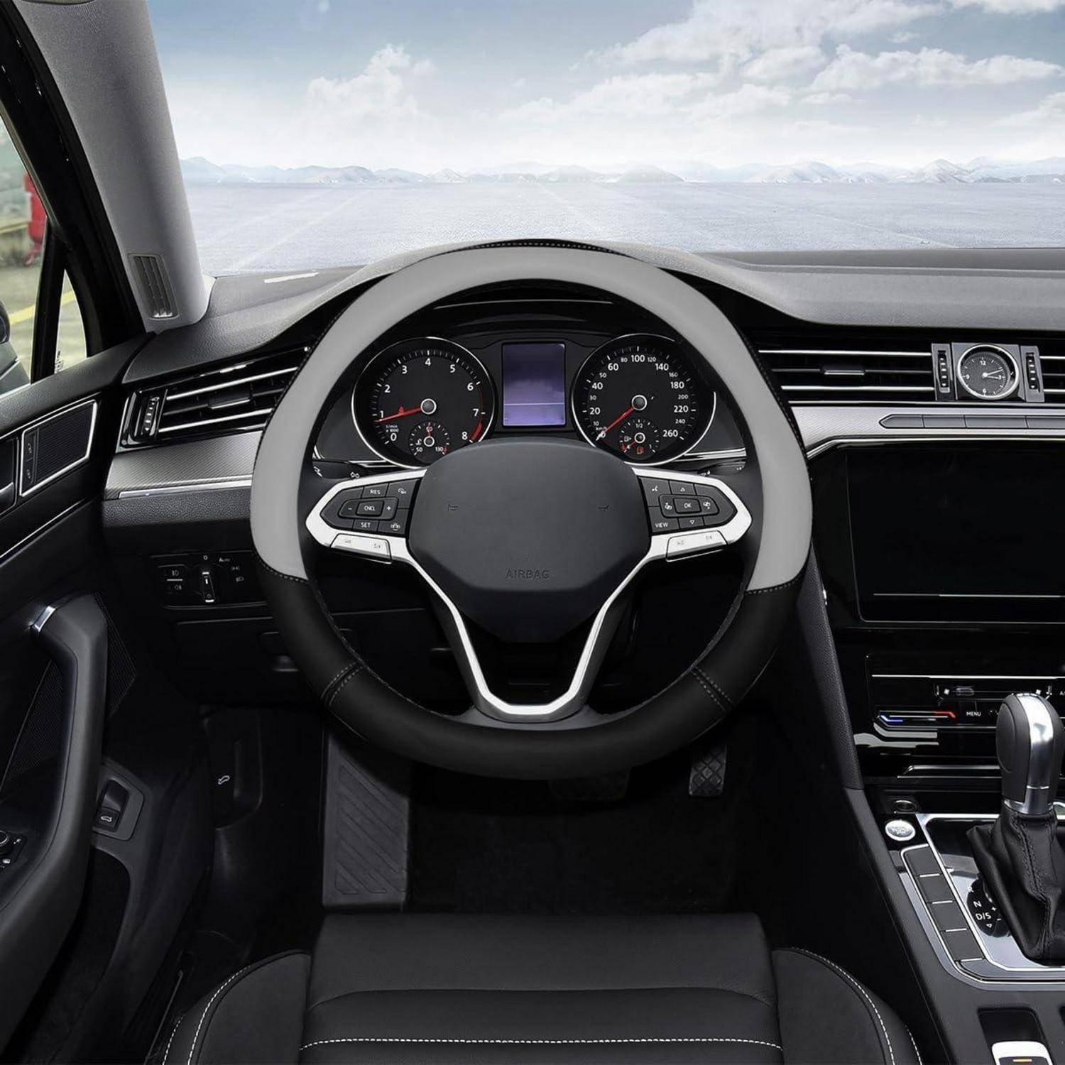 Autoinnenraum aus dem Fahrersitz mit Lenkrad, Instrumententafel, Mittelkonsole und Seeblick durch die Windschutzscheibe.