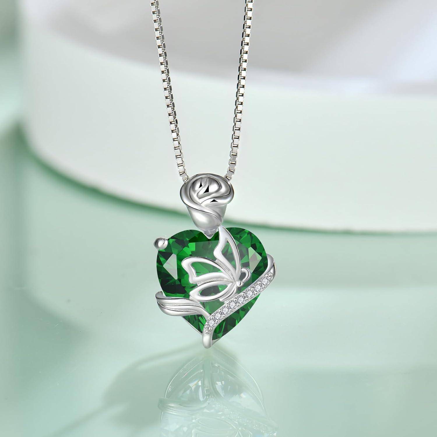 Silberne Anhängerkette mit floralem Design über einem facettierten grünen Edelsteinherzanhänger, verziert mit kleinen transparenten Steinen.