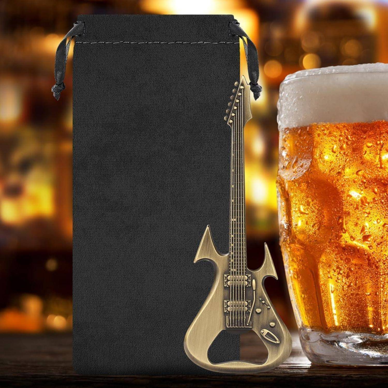 Schwarzer Kordelzugbeutel neben einem goldenen elektrischen gitarrenförmigen Flaschenöffner und einem mattiertem Bierglas auf einem barartigen Hintergrund.