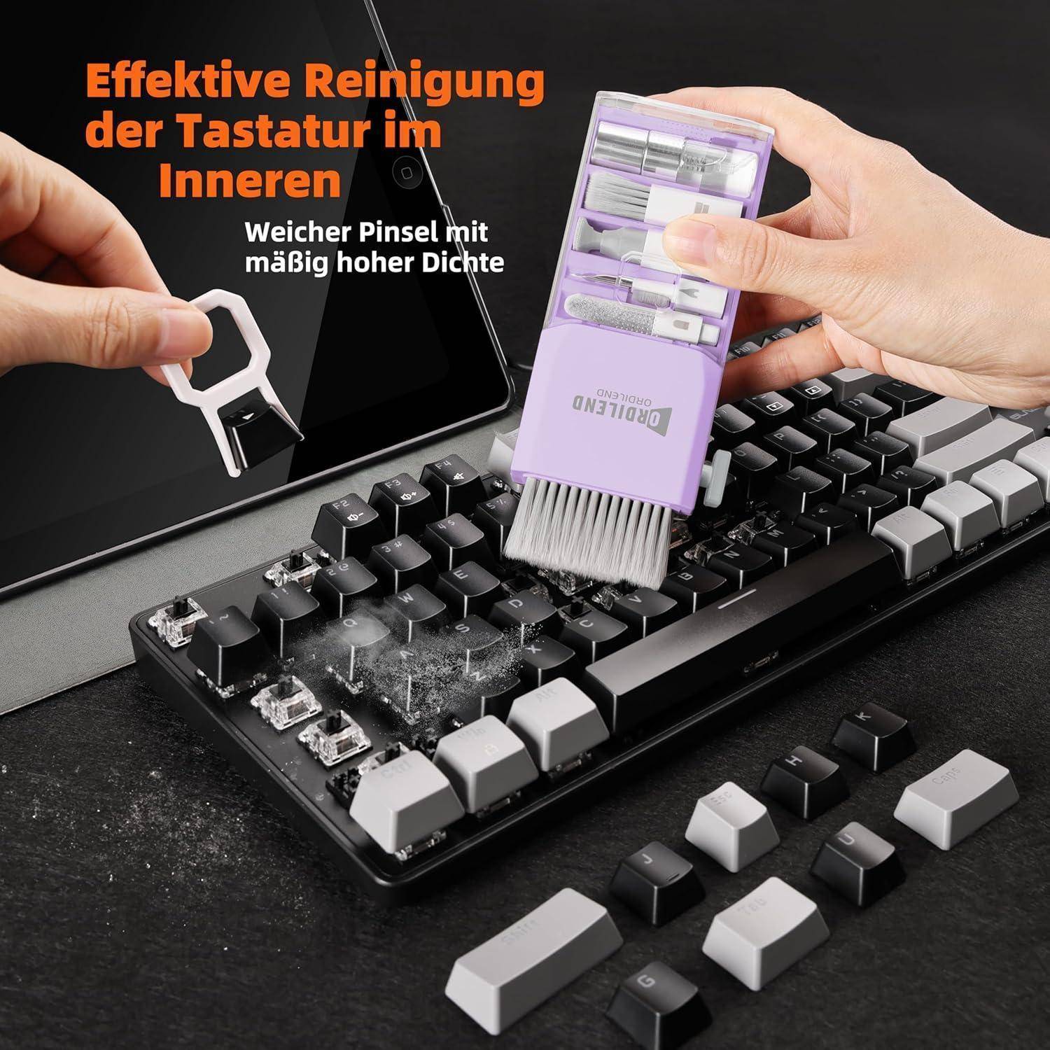 Hände reinigen eine mechanische Tastatur mit einer lila Bürste und einem Tastenkappen-Abzieher; deutscher Text lautet „Effektive Reinigung der Tastatur im Inneren