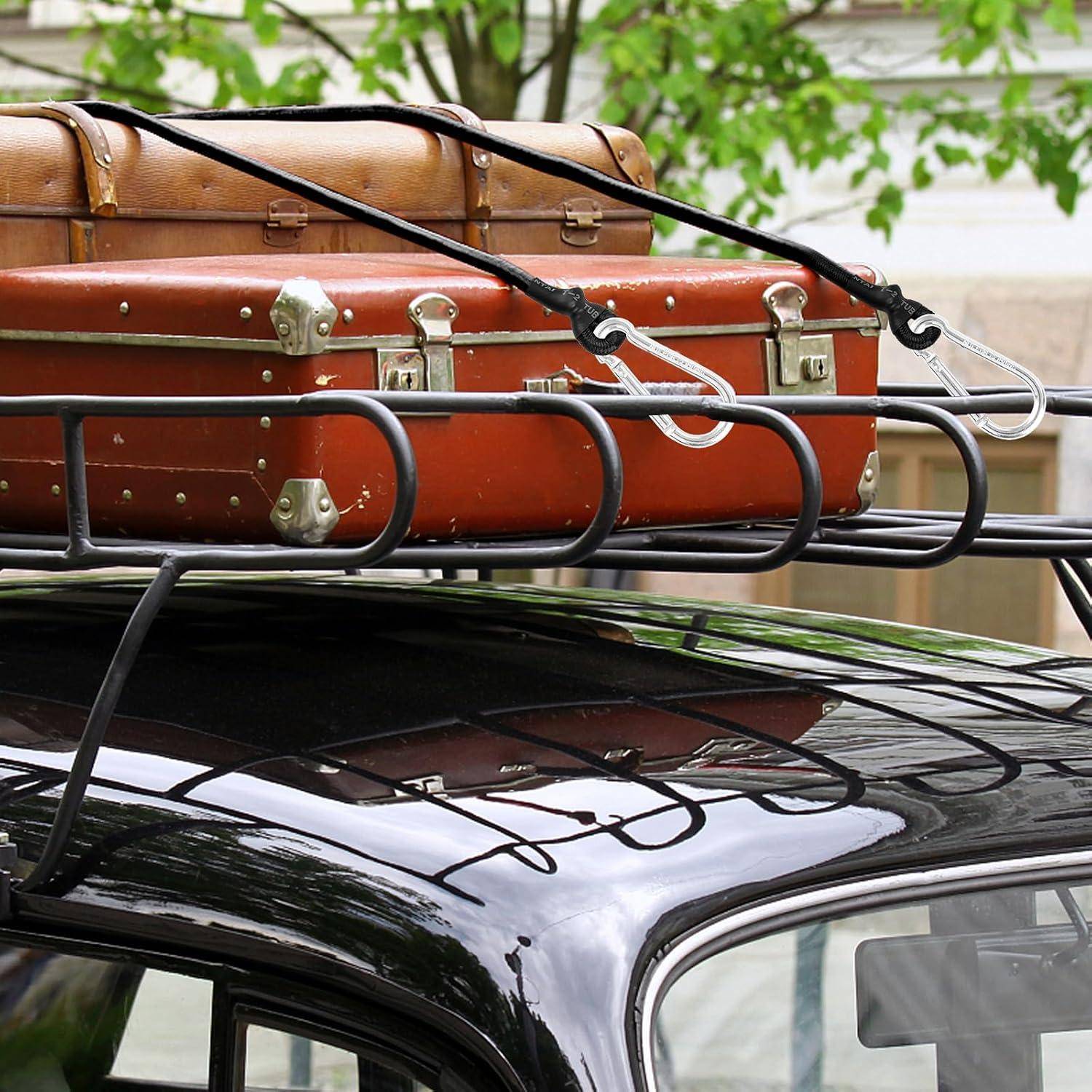 Zwei Vintage-Koffer mit Riemen auf einem Dachgepäckträger auf einem schwarzen Auto befestigt, was auf Reisen oder gepacktes Gepäck hindeutet.
