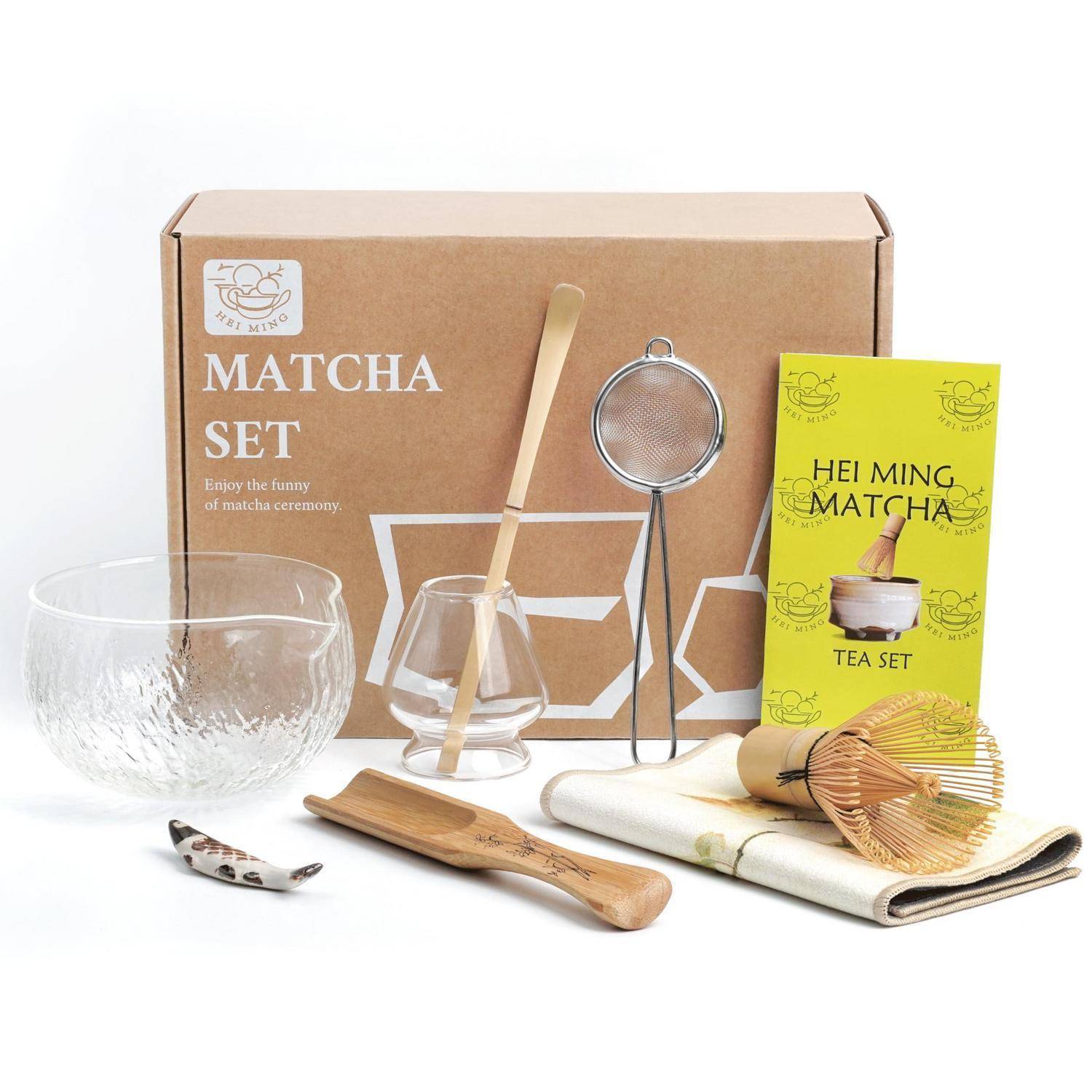 Matcha-Tee-Set mit Box, Glassschale, Besen, Löffel, Sieb, Bestenständer und Anleitungskarte auf weißem Hintergrund.