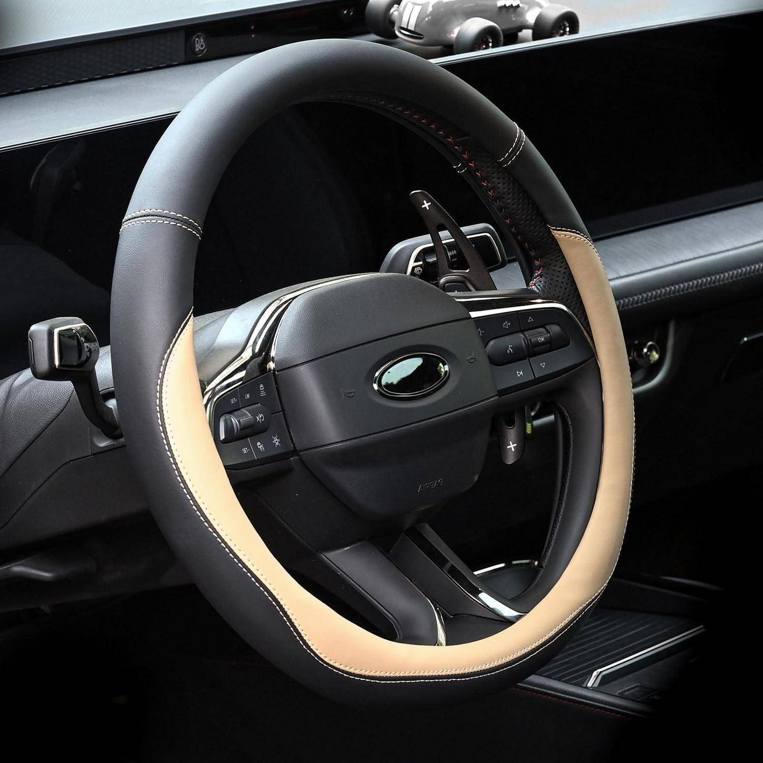 Nahaufnahme eines modernen Autolenkrads mit zweifarbiger schwarzer und beigefarbener Umrandung und integrierten Steuertasten in einem eleganten Armaturenbrett.