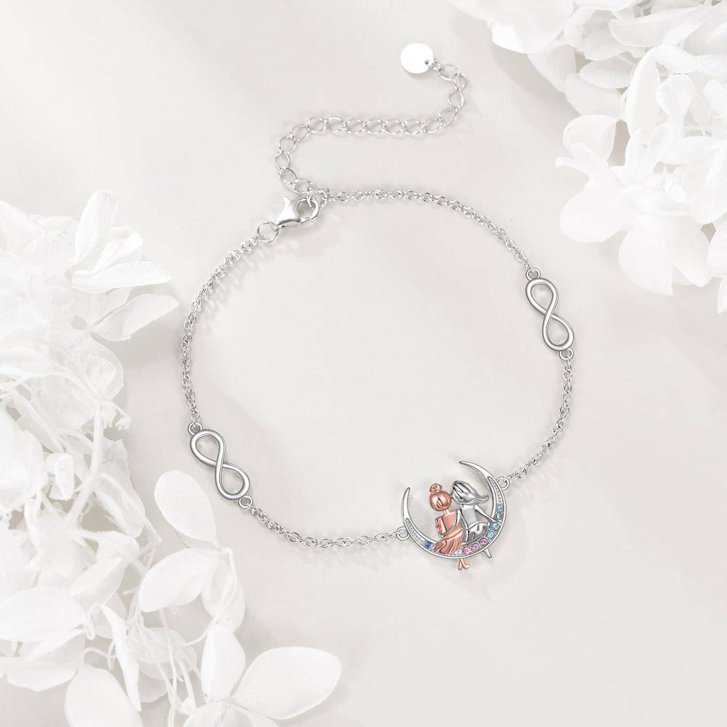 Silbernes Armband mit Unendlichkeits-Anhängern und einem Mond-und-Katzen-Anhänger, fotografiert auf weißem Blumenhintergrund.