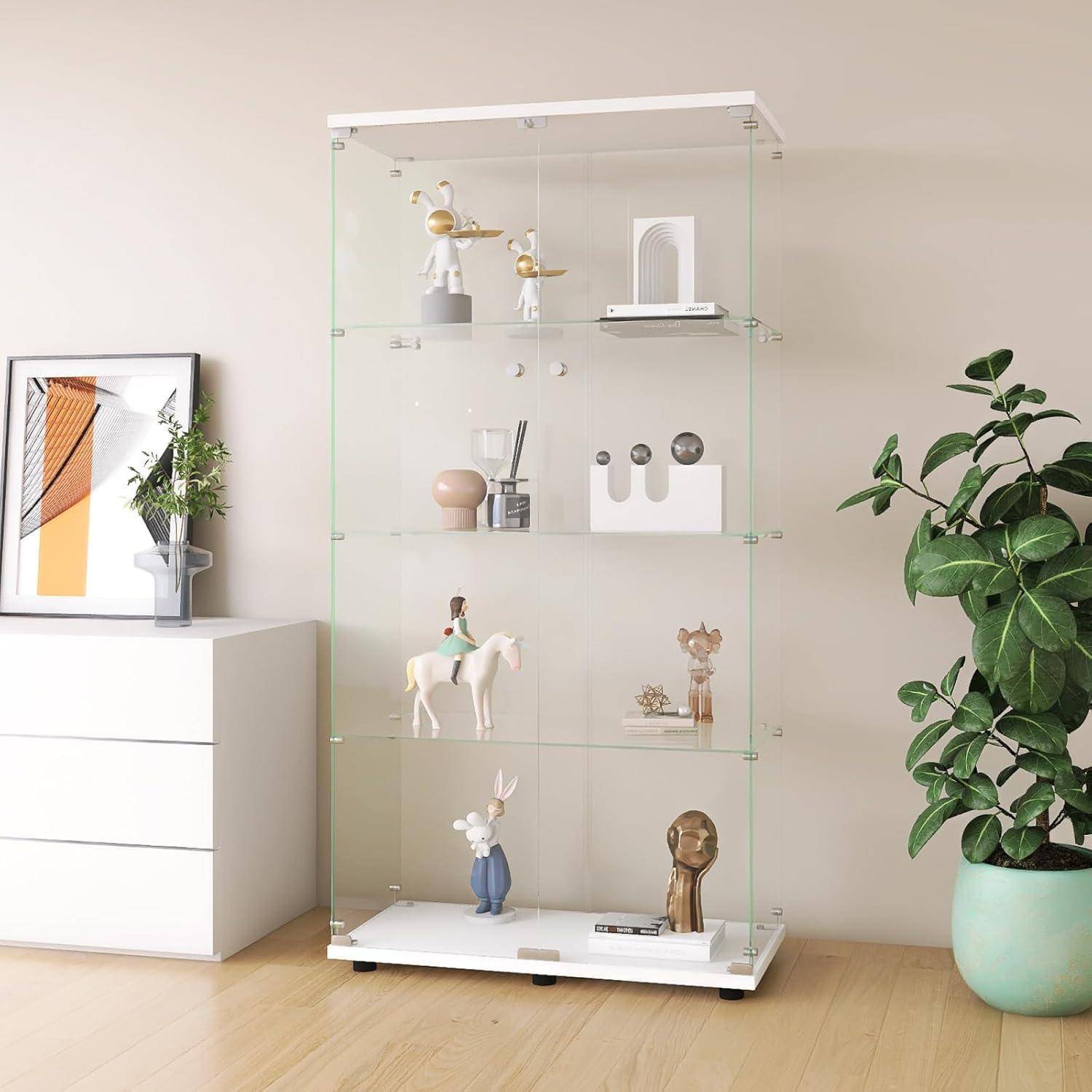 Glassschrankvitrìne mit Regalen, auf denen kleine Figuren und Dekoration stehen, neben einer weißen Kommode und einer Topfpflanze in einem hellen Zimmer.