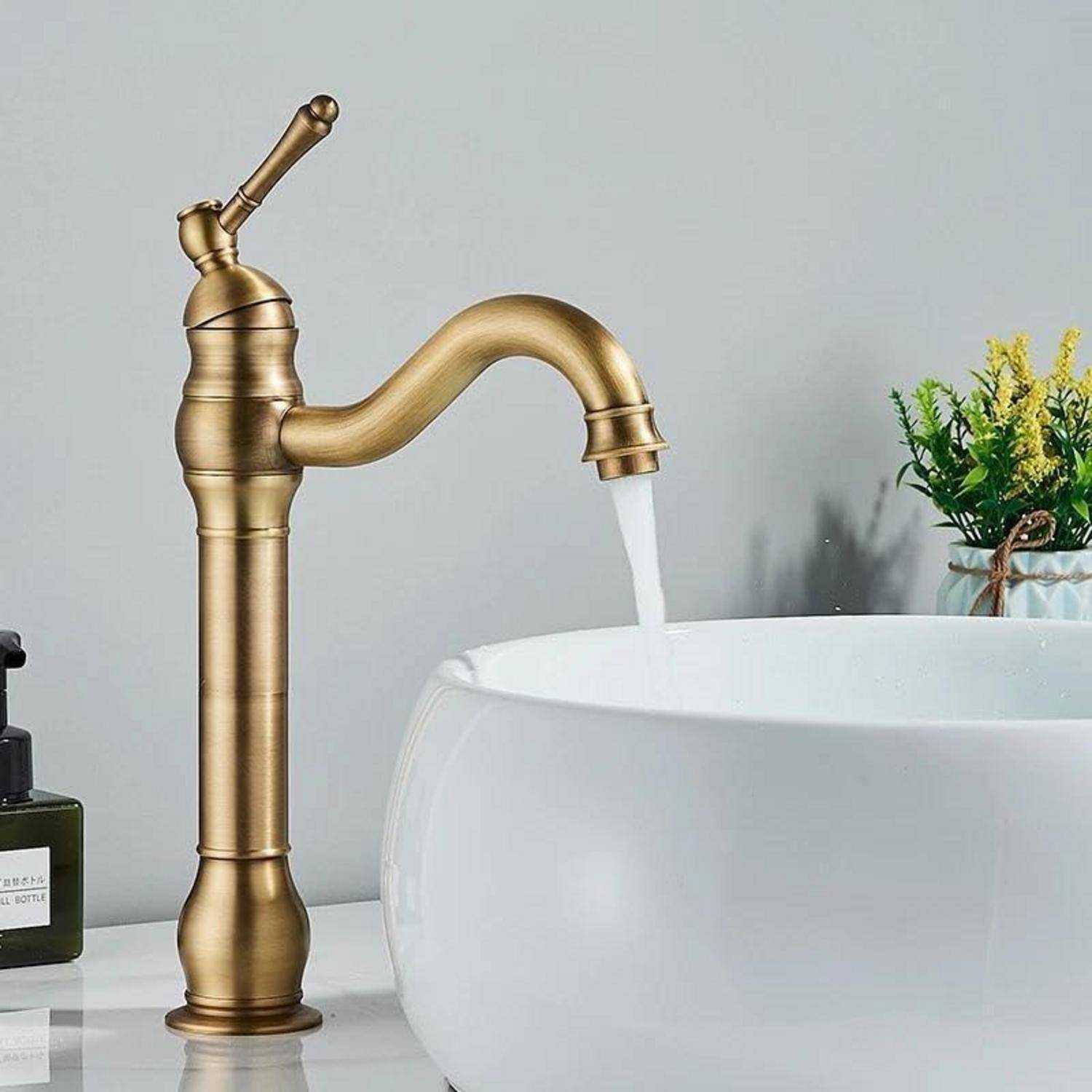 Messingspülenbecken-Wasserhahn mit fließendem Wasser in ein weißes Waschbecken auf einer Badezimmerablage, mit kleinen Dekorationselementen im Hintergrund.