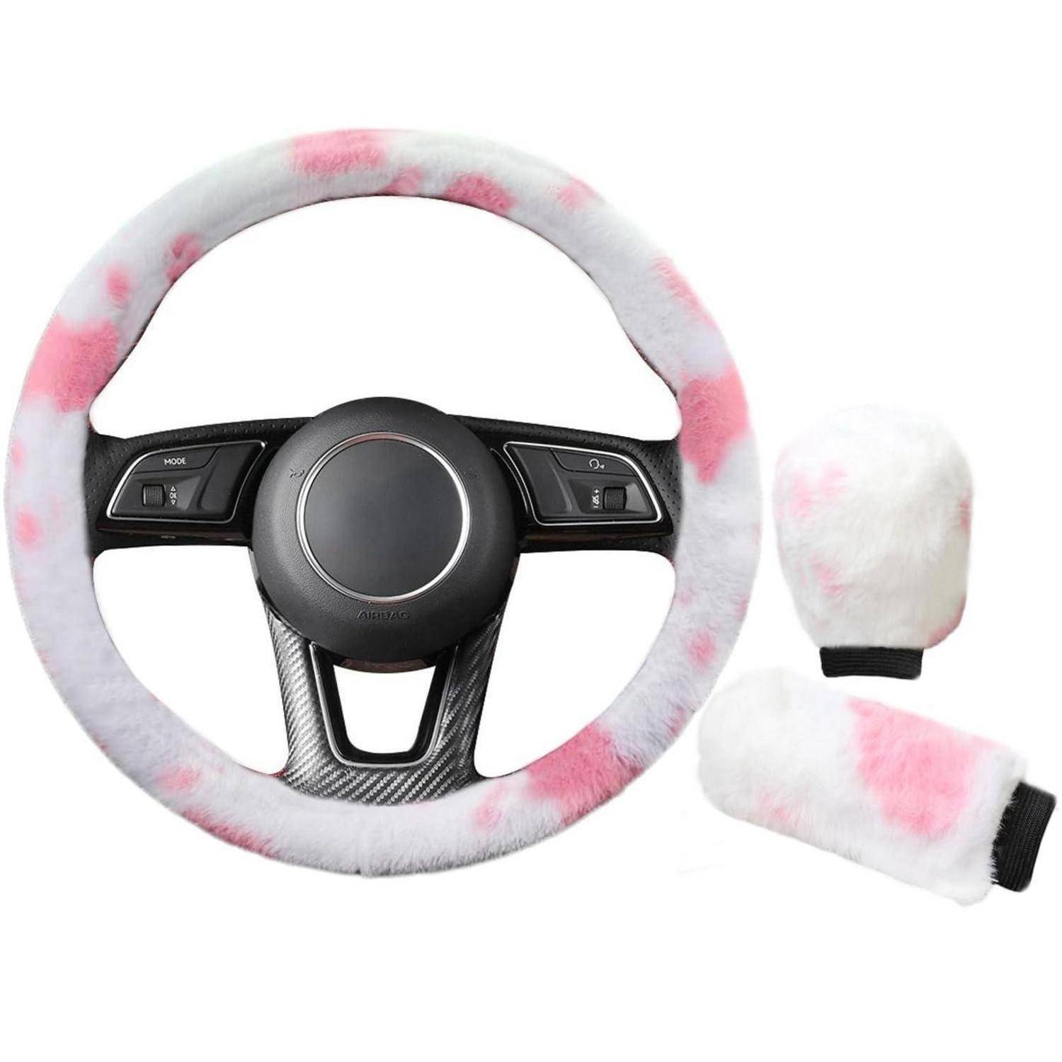 Flauschiger rosa und weißer Lenkradbezug mit passenden Schaltknauf- und Handbremsen-Bezügen auf weißem Hintergrund dargestellt.
