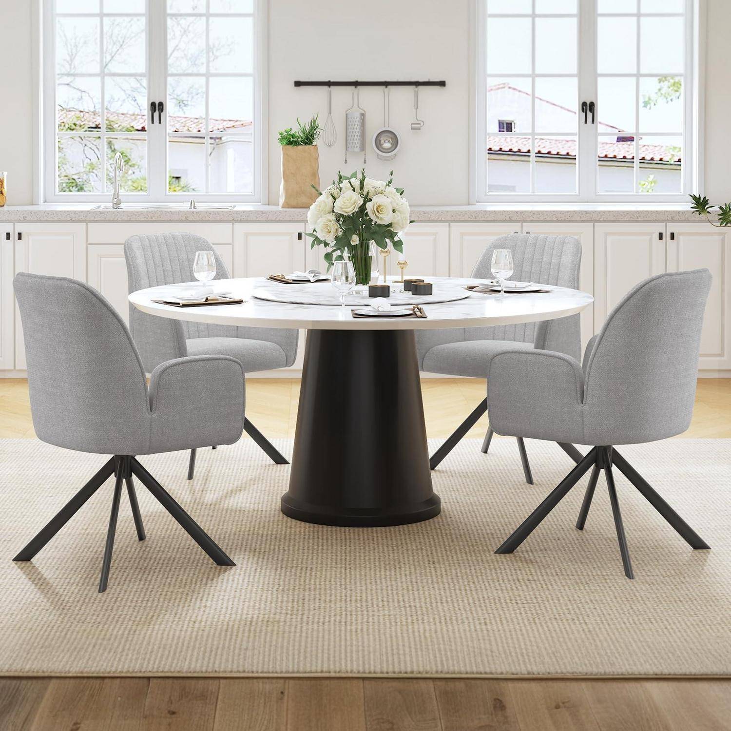 Modernes Esszimmer mit einem runden weißen Tisch, vier grau gepolsterten Stühlen und einer Blumendekoration in der Mitte in einer hellen Küchenumgebung.