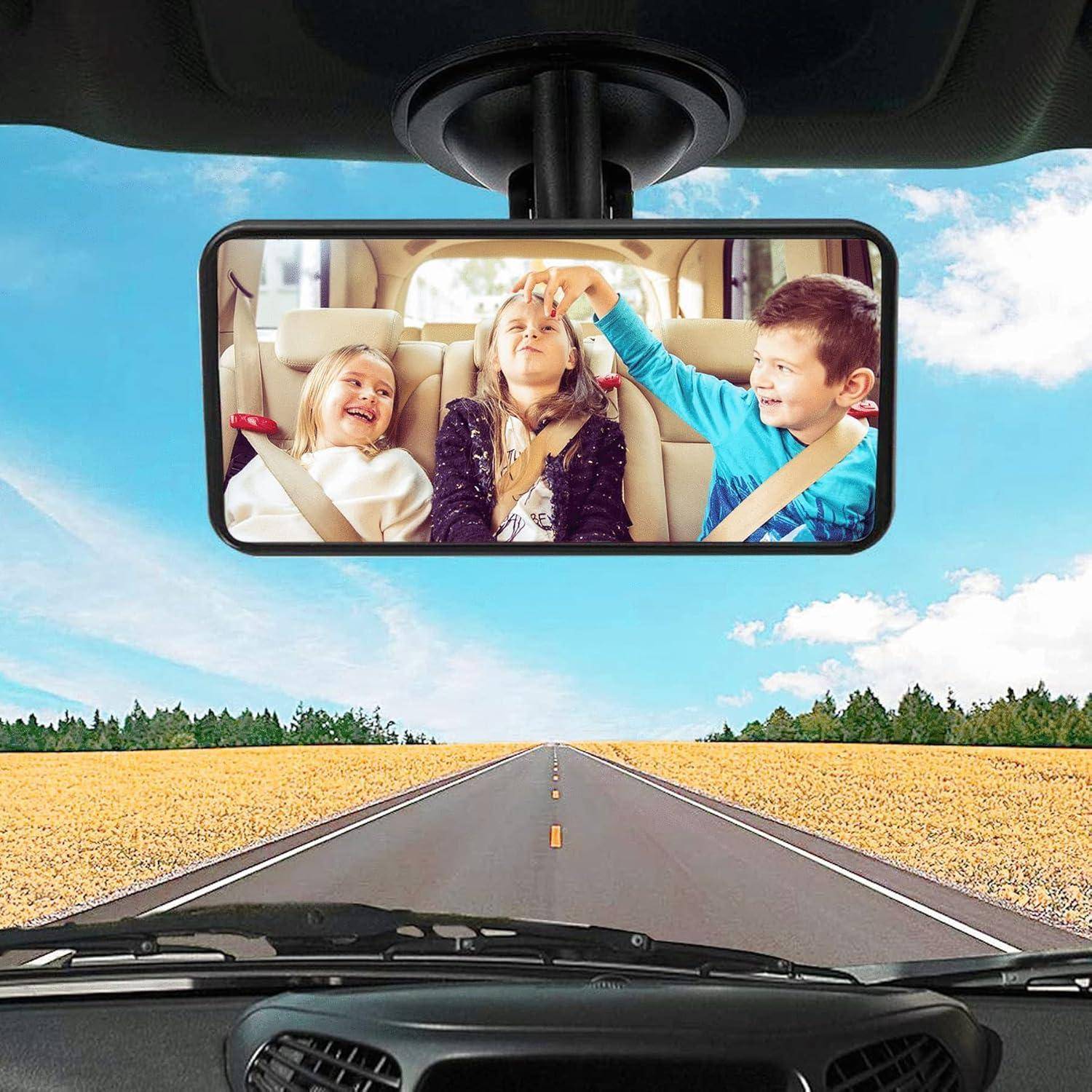 Der Rückspiegel zeigt drei Kinder auf der Rückbank eines Autos, die lachen und spielen, während sie auf einer offenen Straße fahren.