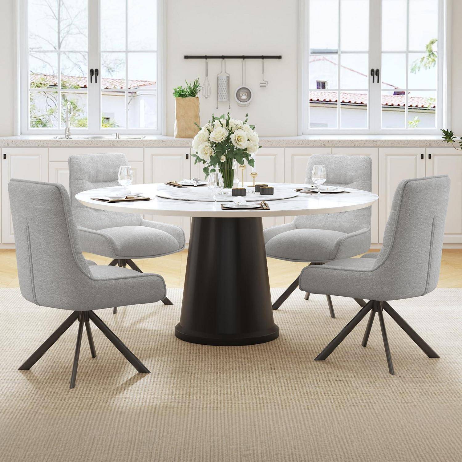 Ein modernes Esszimmer mit einem runden weißen Tisch, vier grau gepolsterten Stühlen, einer Blumenmittelstückdekoration und hellen Fenstern im Hintergrund.
