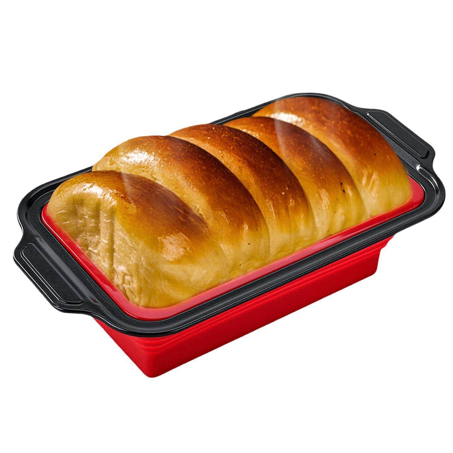 Laib Brot, das in einer roten rechteckigen Kastenform mit schwarzen Griffen auf weißem Hintergrund gebacken wurde.