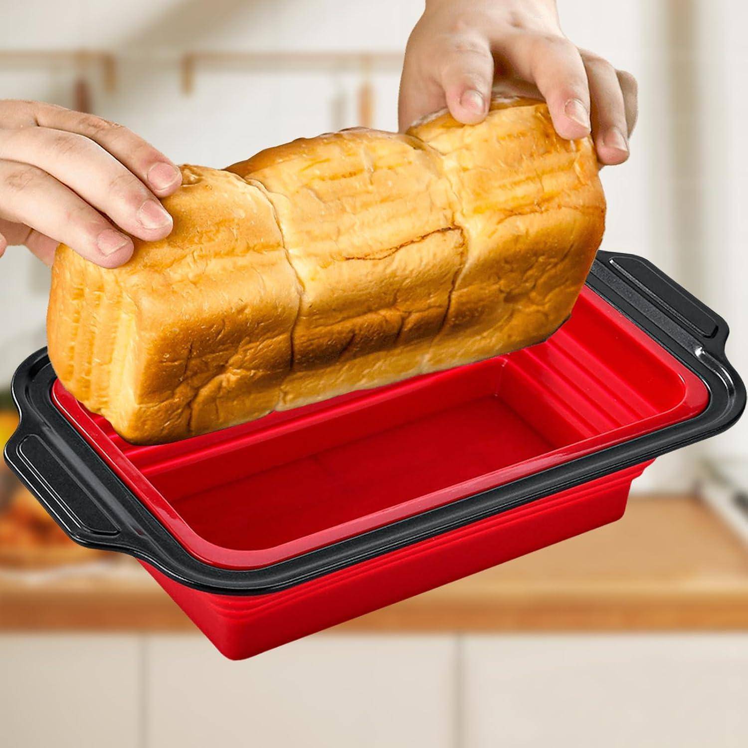 Hände heben einen Laib Brot aus einer roten zusammenklappbaren Kastenform mit schwarzen Griffen.