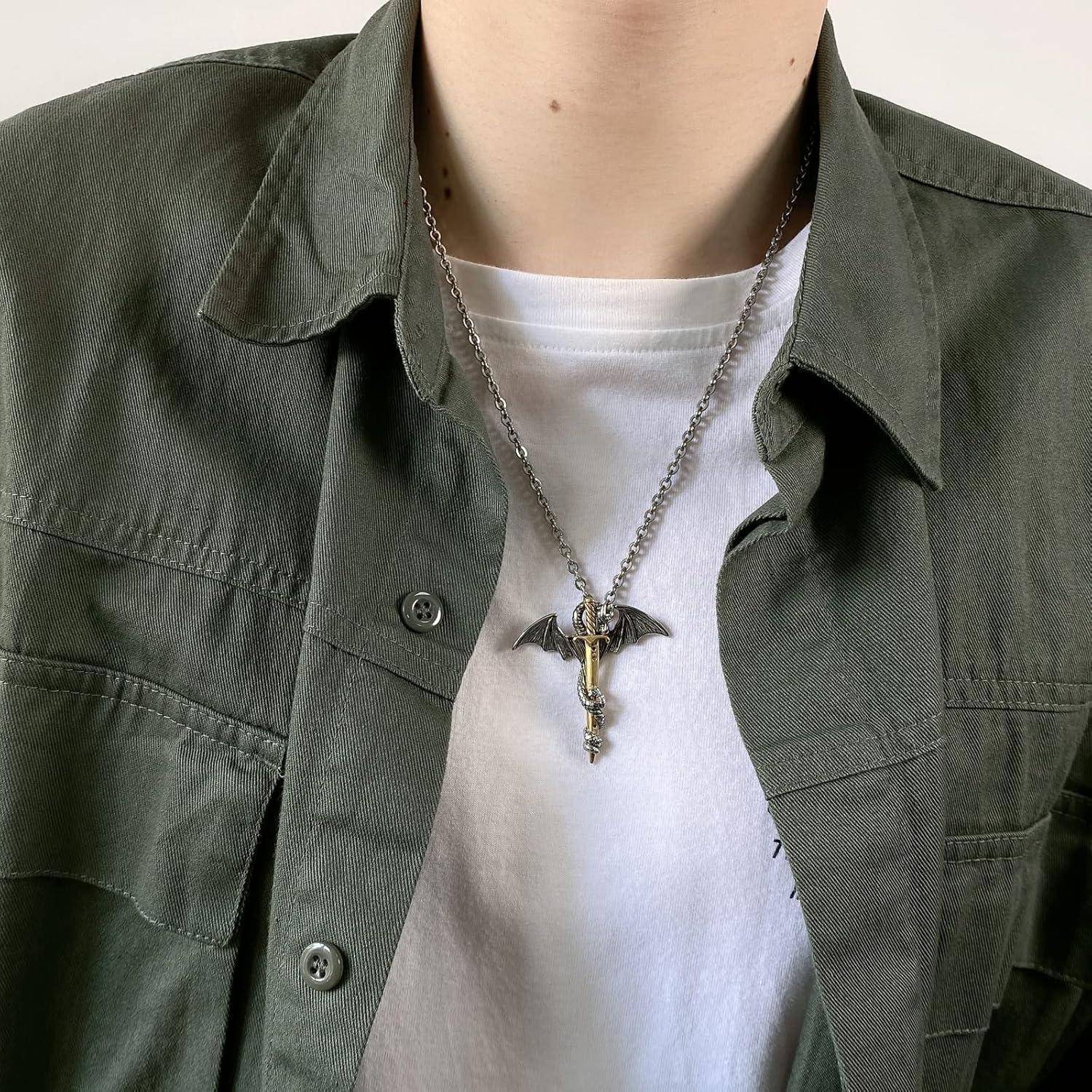 Person, die ein olivgrünes Überhemd und ein weißes T-Shirt trägt, mit einer silbernen Halskette, die einen fledermausförmigen Anhänger und einen Schlüsselanhänger zeigt.