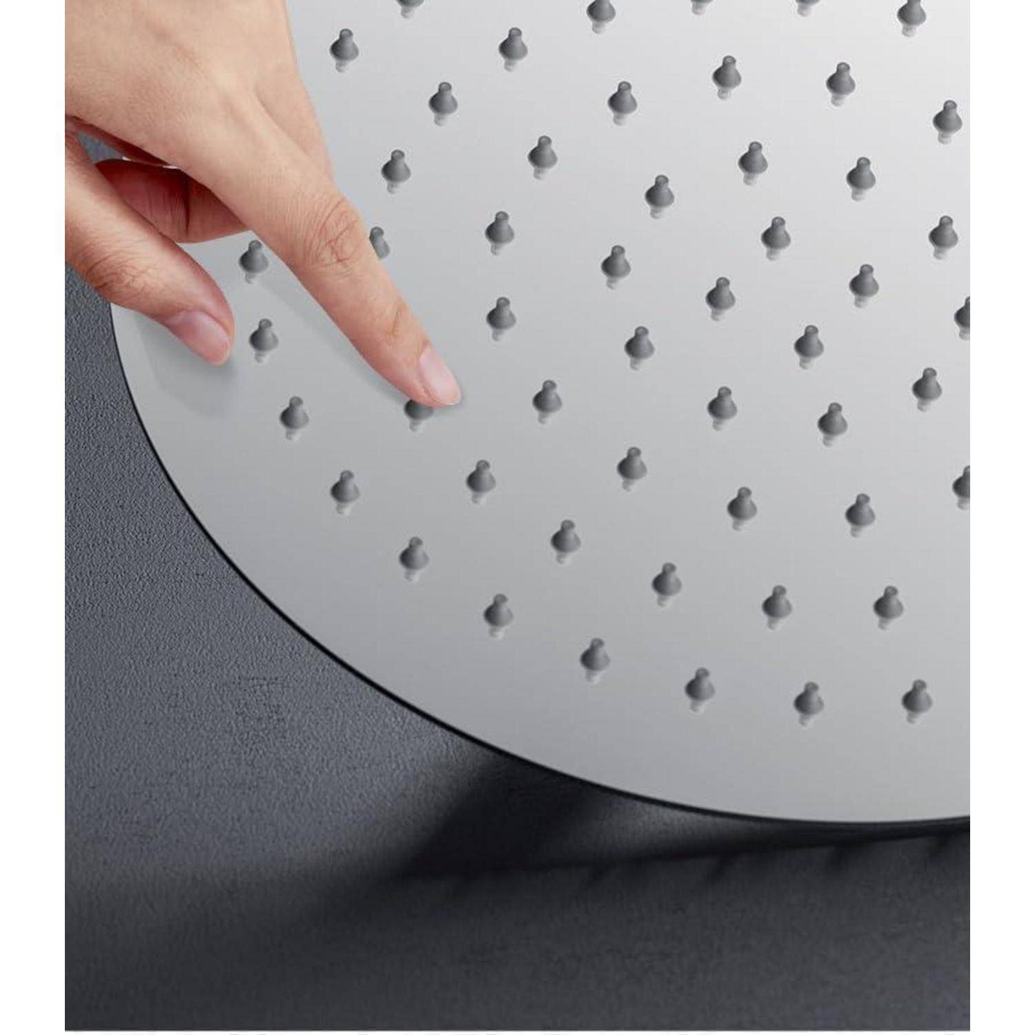 Nahaufnahme einer Hand, die einen runden metallenen Duschkopf mit Gummidüsen gegen einen dunklen Hintergrund berührt.