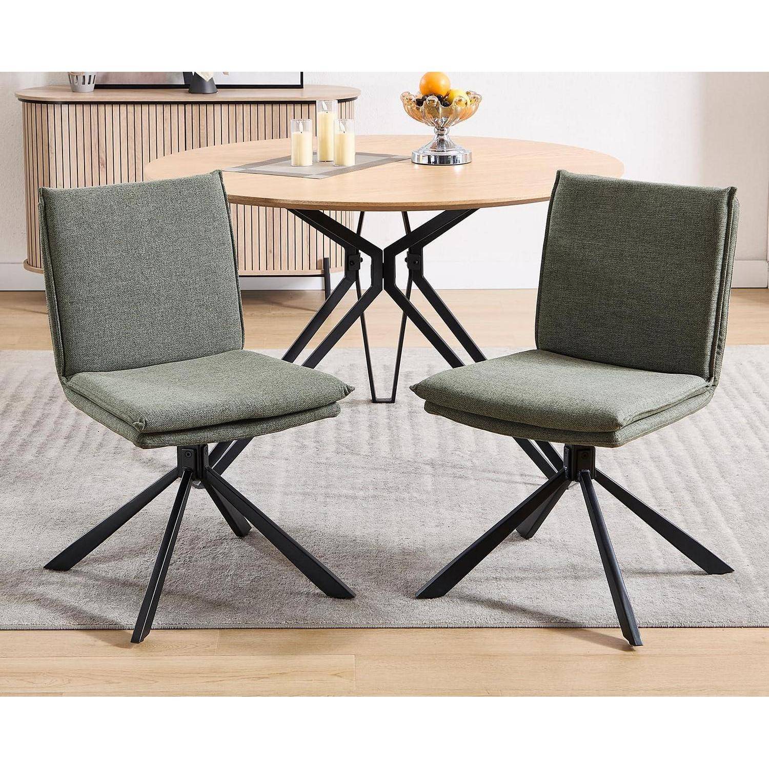 Zwei grüne gepolsterte Drehstühle mit schwarzen Metallgestellen neben einem runden Holzesstisch in einem modernen Esszimmer.