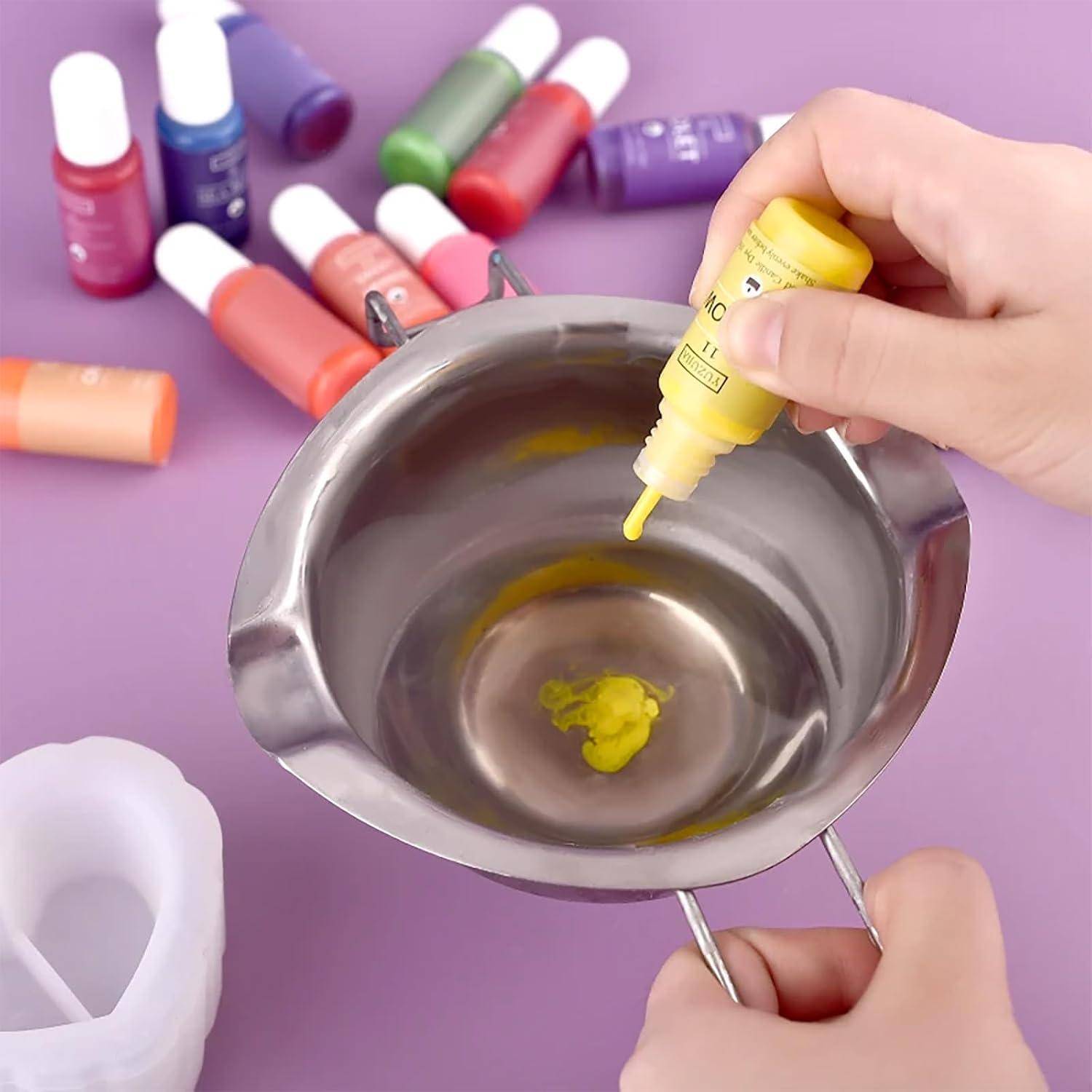 Hände gießen gelbe Flüssigkeit aus einer Tropferflasche in eine Metallmischschüssel, während verschiedenfarbige Farbflaschen auf einer violetten Oberfläche verstreut sind.