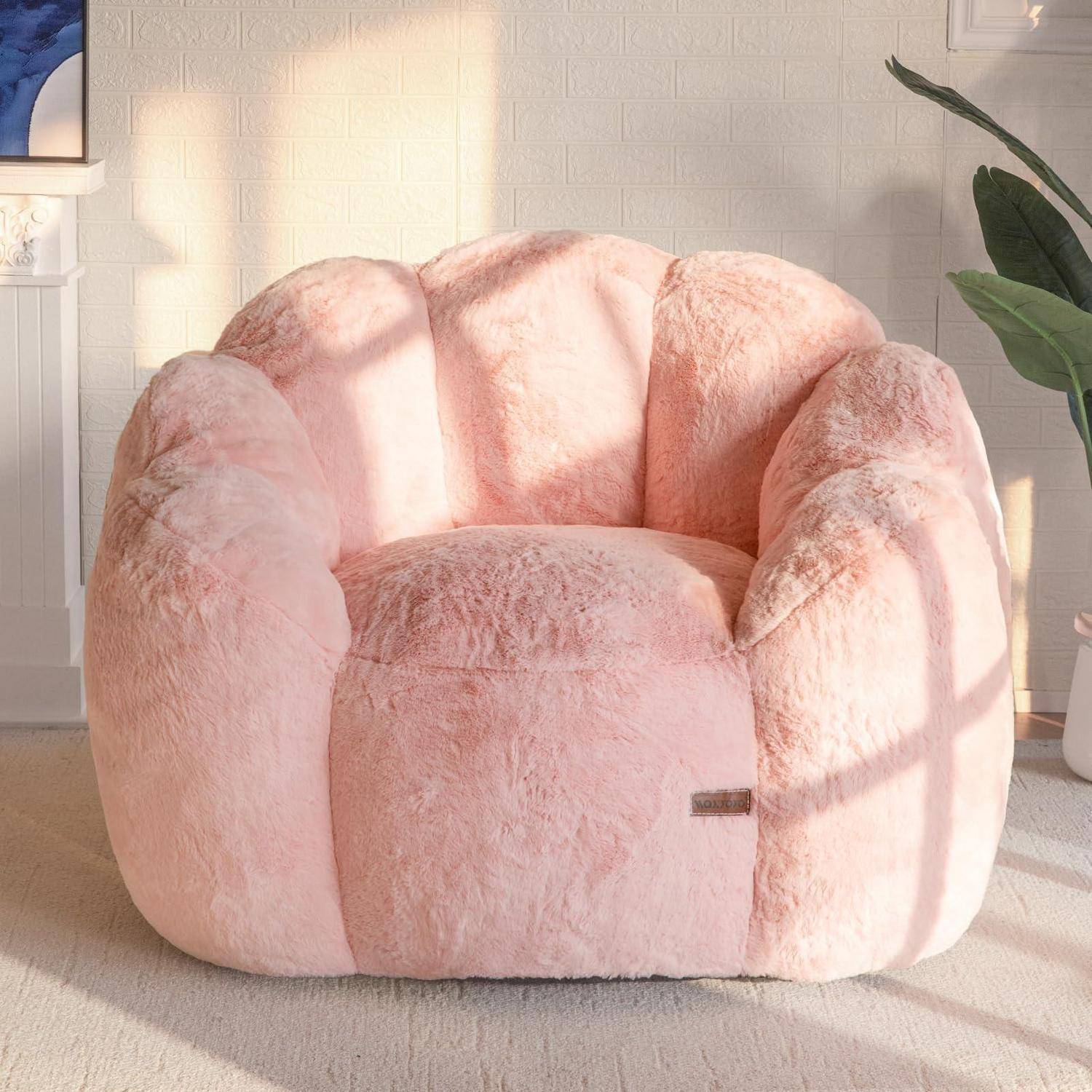Rosa flauschiger Sessel in einem sonnendurchfluteten Zimmer mit Pflanze und Teppich, Vorderansicht.