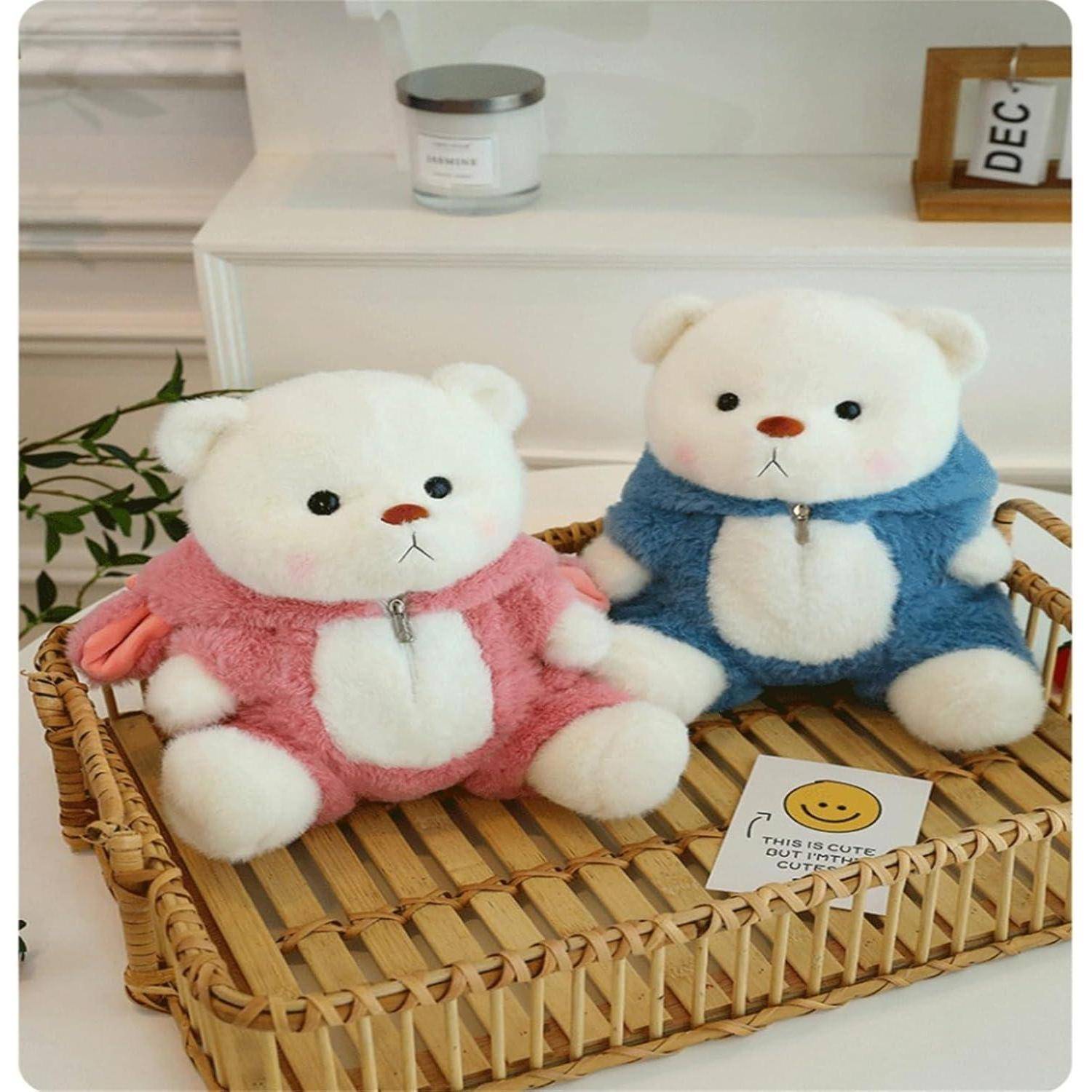Zwei plüschige Teddybären in rosa und blauen Kapuzenpullovern sitzen auf einem Weidentablett, mit einer kleinen Karte 