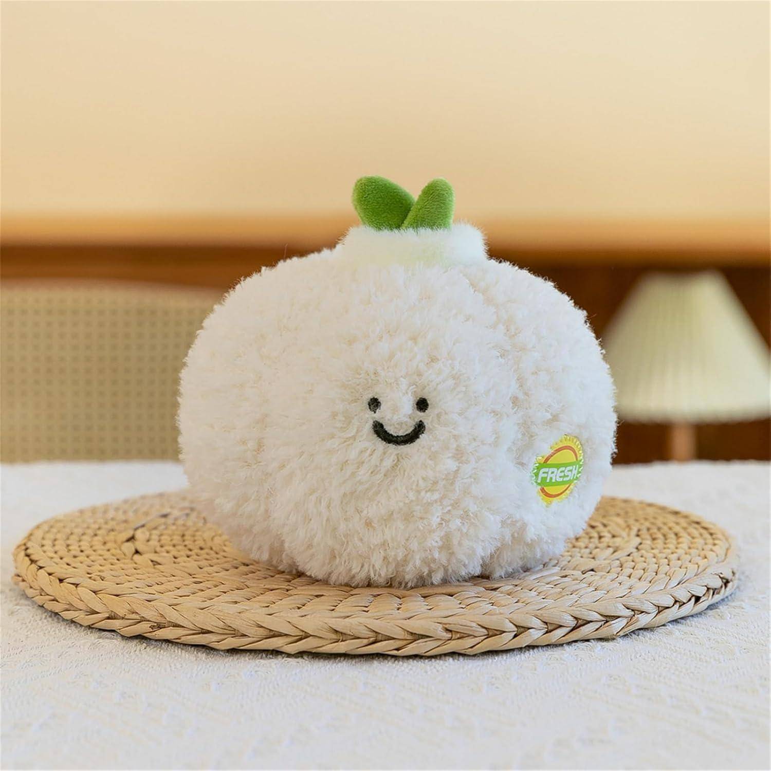 Ein flauschiges weißes rundes Plüschspielzeug mit lächelndem Gesicht und grünen Blättern oben sitzt auf einer geflochtenen Platzdecke auf einem Bett.