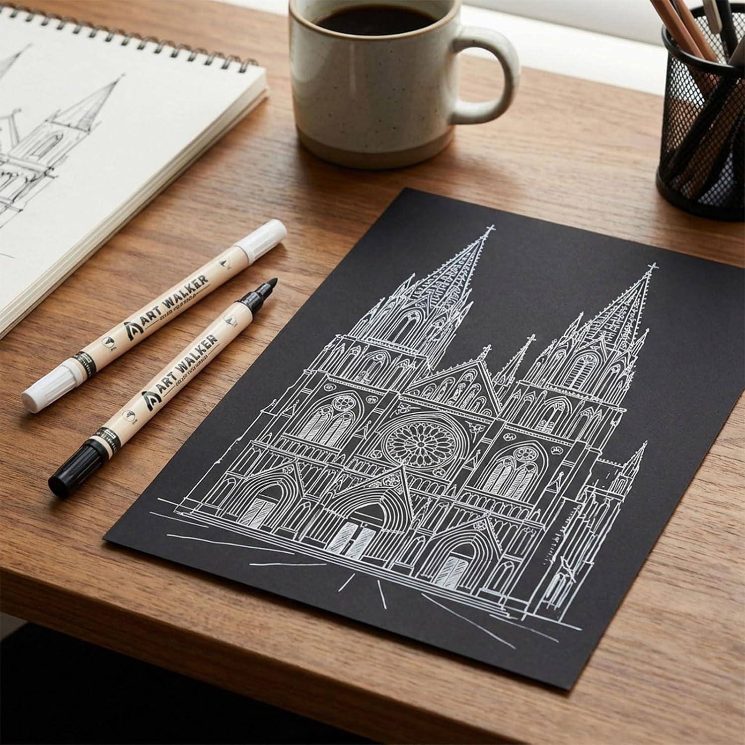 Weiße Linienzeichnung einer Kathedrale mit Zwillingstürmen auf schwarzem Papier, umgeben von Zeichenstiften, einem Skizzenbuch und einer Tasse auf einem Holzschreibtisch.