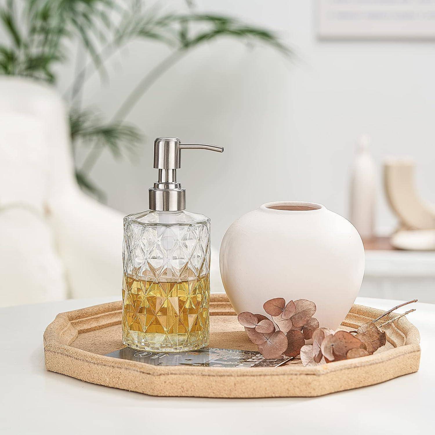 Glassseifenspender und weiße Keramikvase mit getrockneten Blumen auf einem Holztablett in einer minimalistischen Raumgestaltung