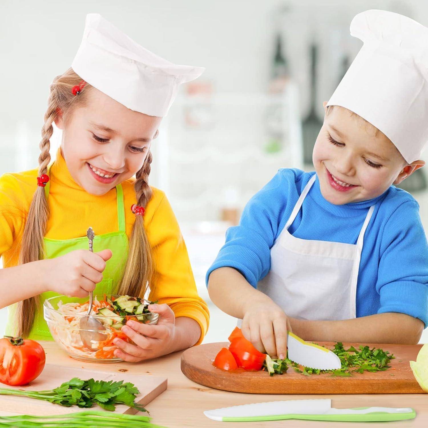Zwei Kinder in Kochmützen und Schürzen bereiten gemeinsam einen Salat zu, schneiden Gemüse klein und mischen Zutaten an einem Küchentisch.