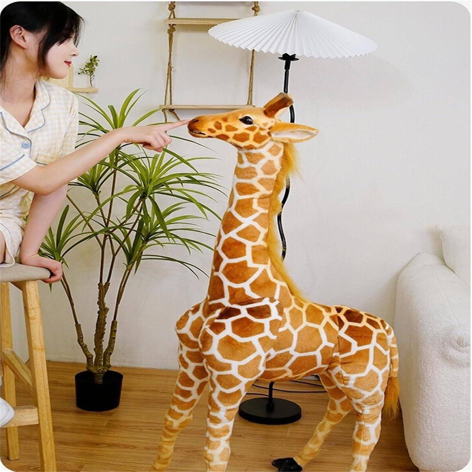 Frau berührt die Nase eines giraffenförmigen Plüschtiers, das drinnen neben einer Pflanze und einer Stehlampe steht.