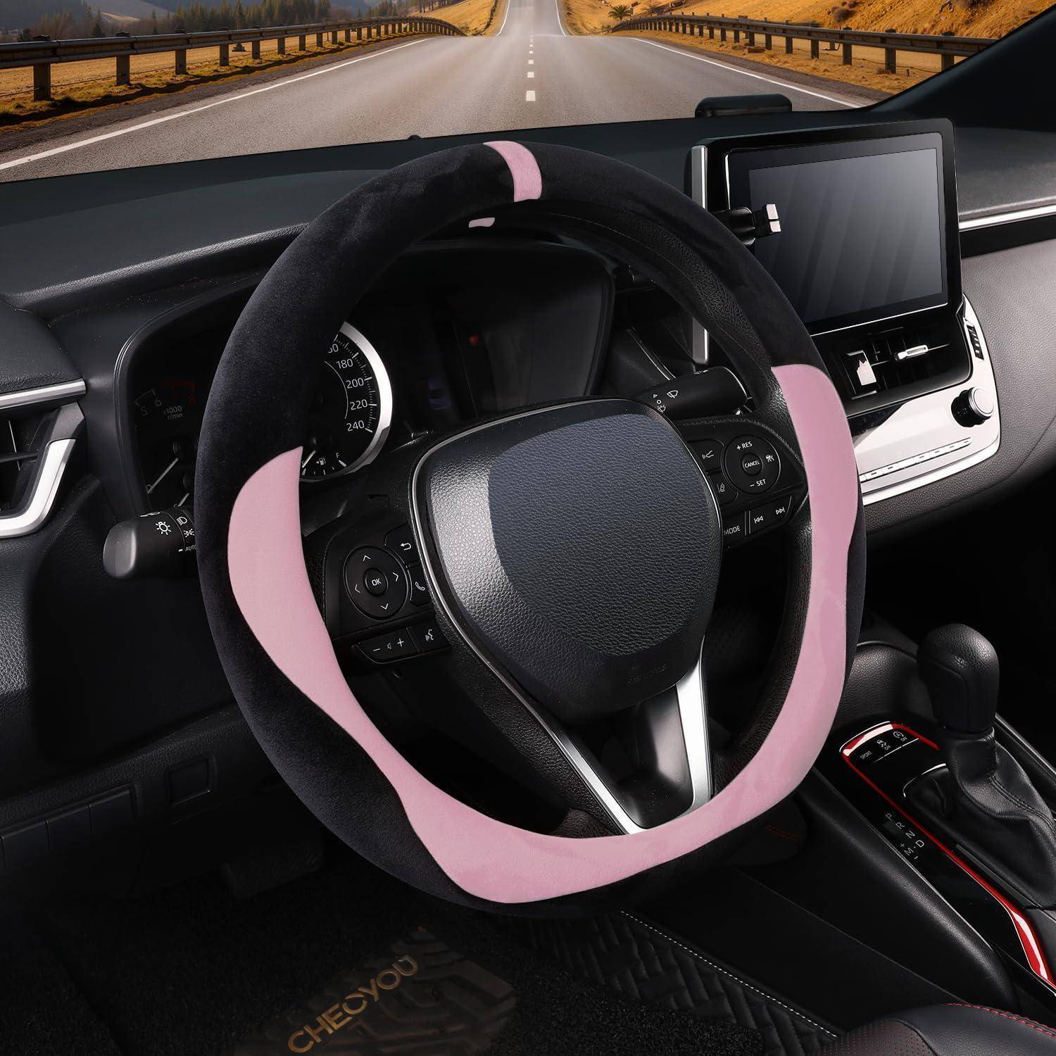Autoinneres mit einer rosa Lenkradabdeckung, Dashboard-Bildschirm und Schaltknüppel, aus der Perspektive des Fahrerplatzes auf einer offenen Straße betrachtet.