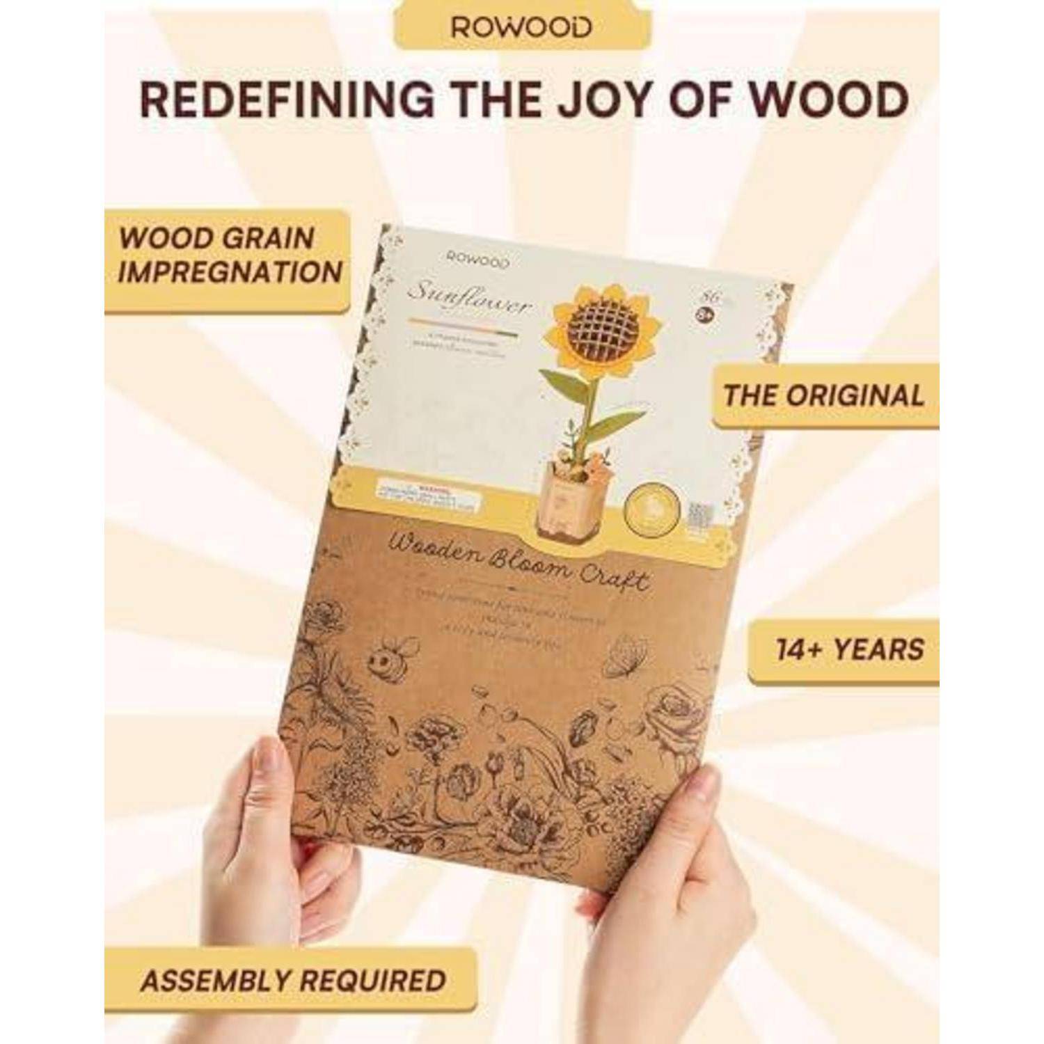 Hände, die eine Rowood Holz-Blüten-Handwerkskasette mit Sonnenblumenbild und Text halten, der Holzfaserimprägnierung, Originaldesign, ab 14 Jahren und Zusammenbau erforderlich bewirbt.