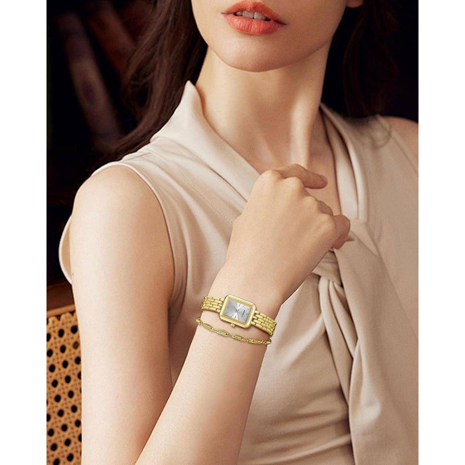 Nahaufnahme einer Frau, die eine goldene Armbanduhr und ein Armband trägt und ein beiges ärmelloses Top trägt, das den Schmuck und den Fashion-Stil hervorhebt.