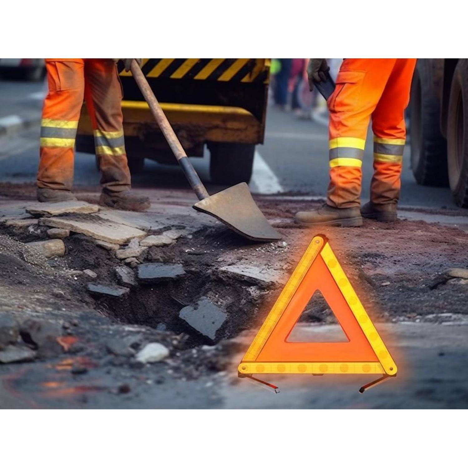 Straßenreparaturarbeiter mit einer Schaufel, die ein beschädigtes Schlagloch ausbessern, gekennzeichnet durch ein leuchtendes orangefarbenes Warndreieck im Vordergrund.