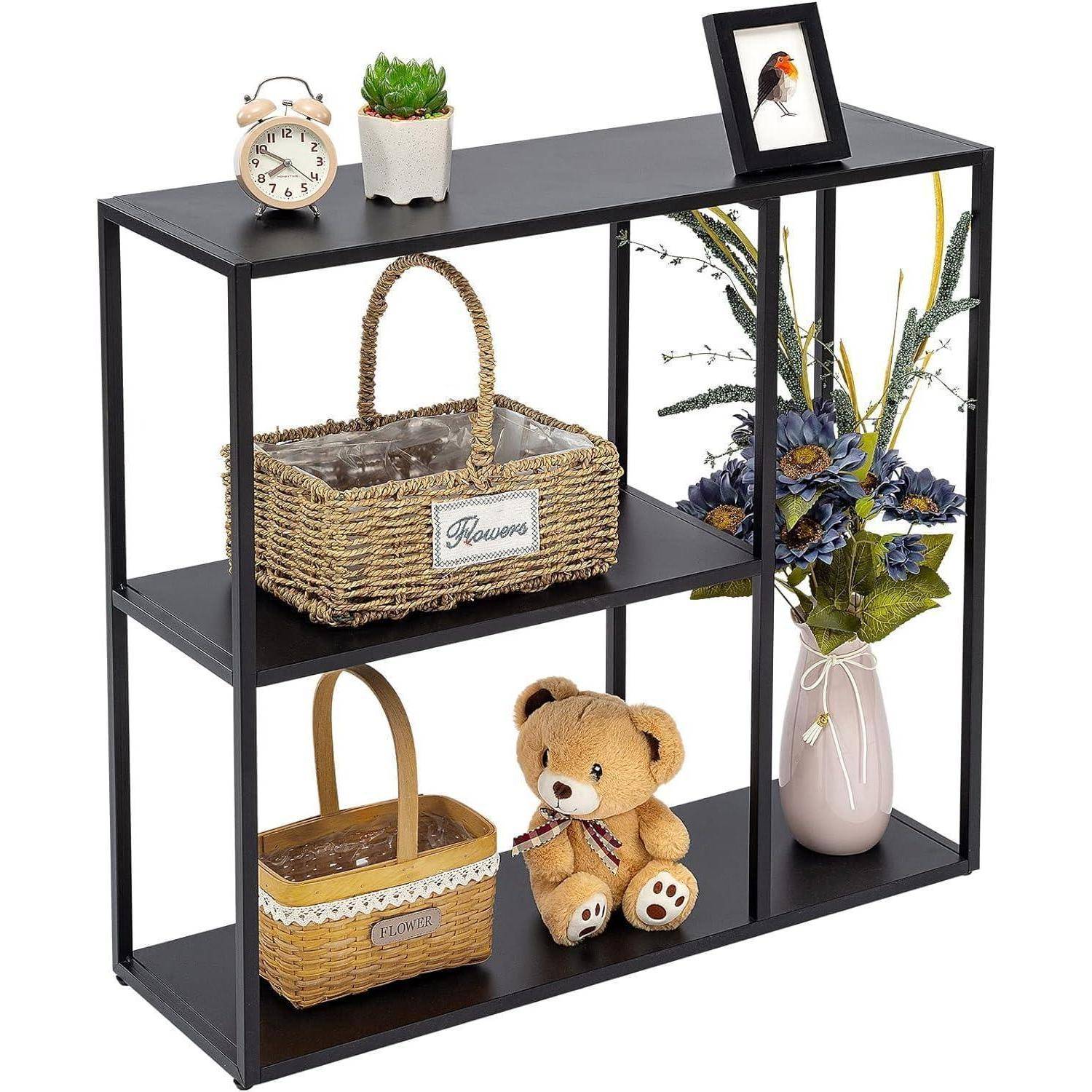Schwarzes Metall-Wandregal mit drei Ebenen, das Weidenkörbe mit Blumen, einen Teddybären, eine Vase mit Blumen, eine Uhr, eine Pflanze und ein gerahmtes Vogelfoto hält.